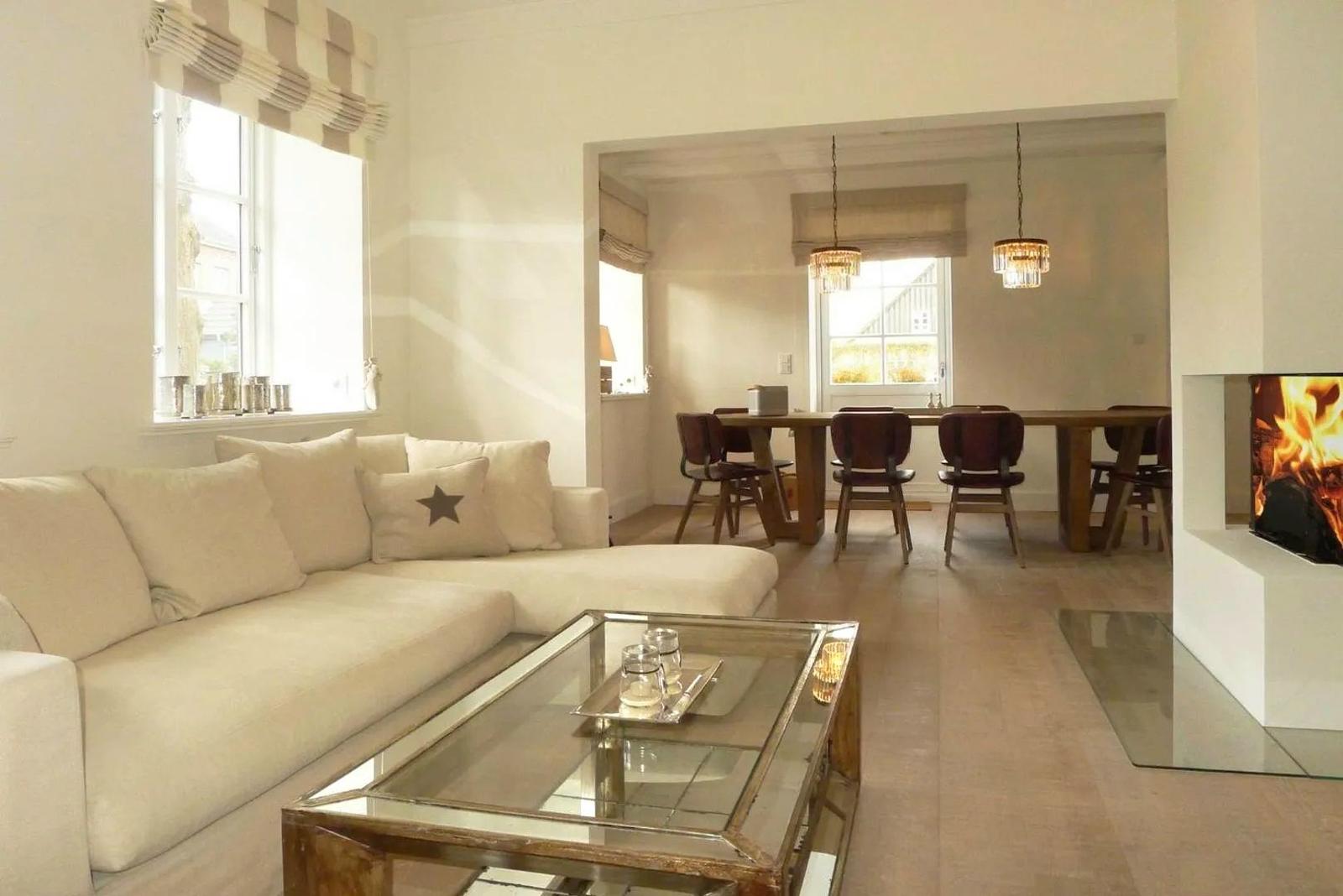 Wohn- und Essbereich mit Sofa, Tisch und Kamin.