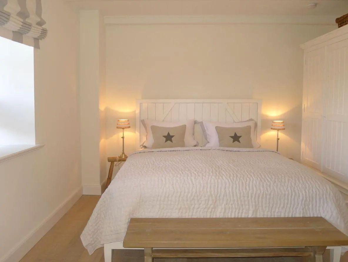 Schlafzimmer mit Bett, Nachttischen und Fenster