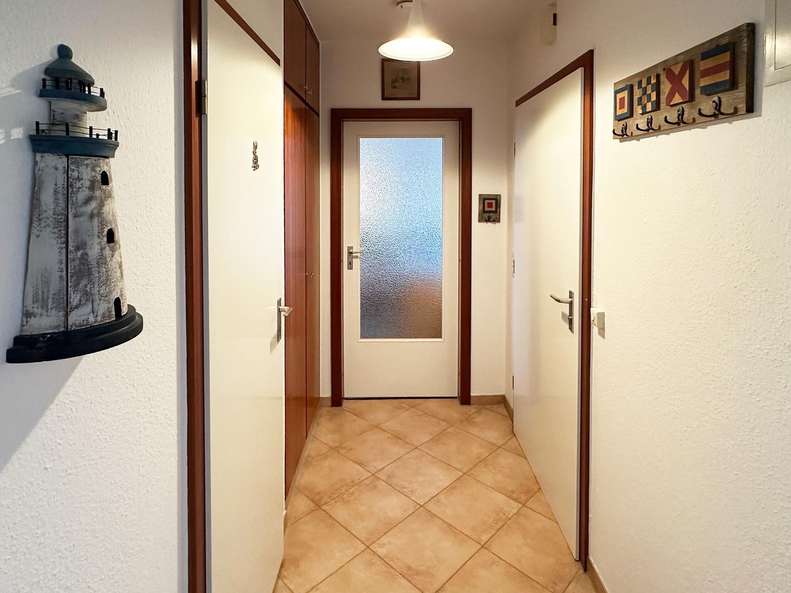 Flur mit Tür, Wandlampe und Navigationszeichen an der Wand.
