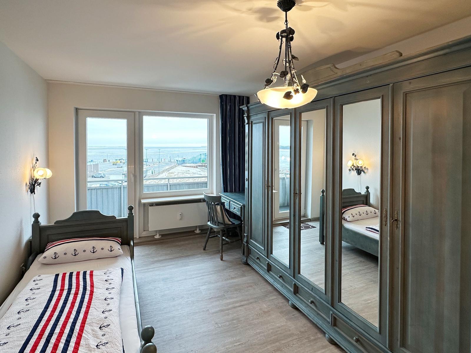 Schlafzimmer mit Blick aufs Meer, großes Spiegelschrank und Schreibtisch.