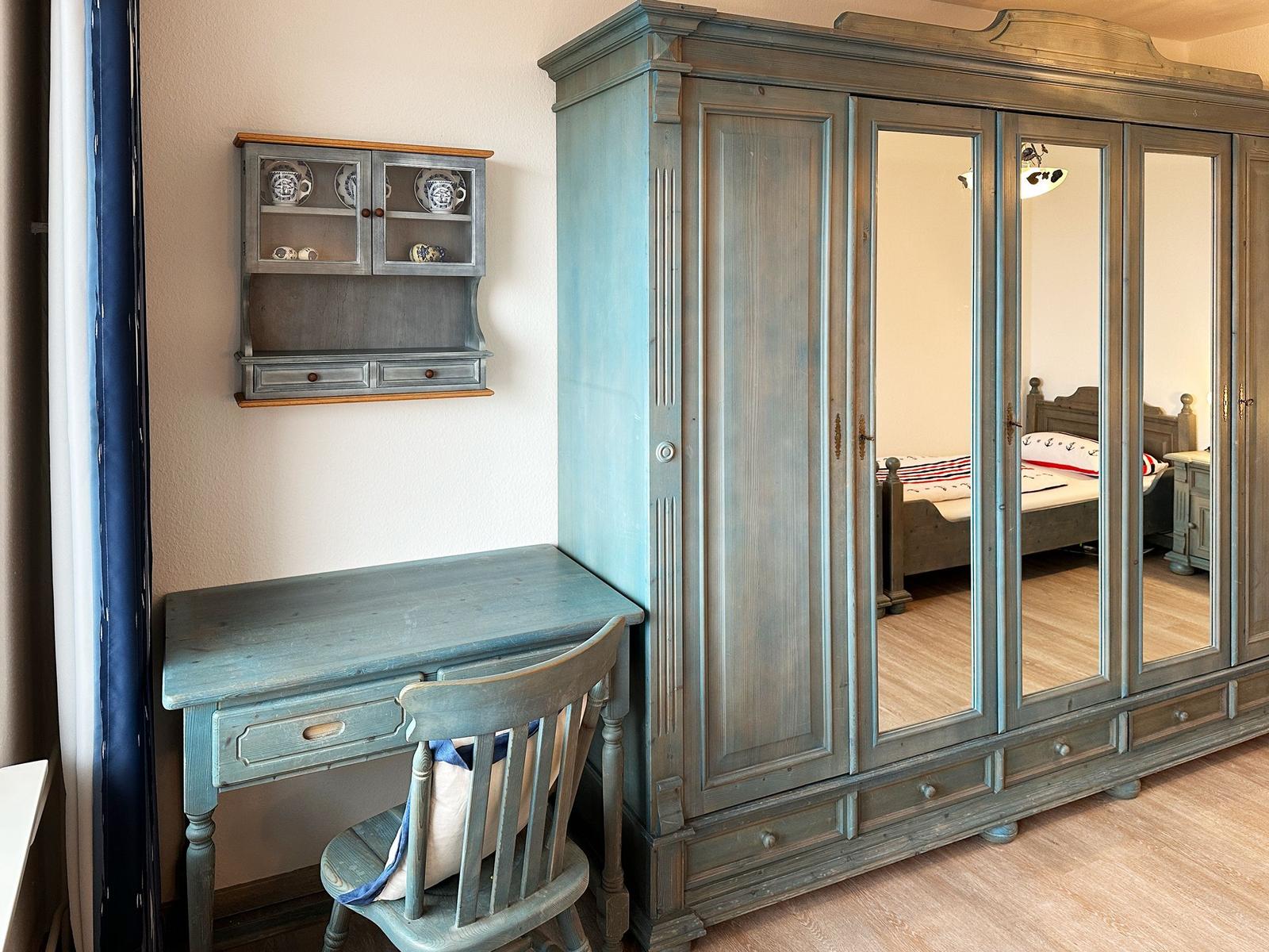 Schreibtisch und Kleiderschrank mit Spiegeltüren in einem Schlafzimmer.
