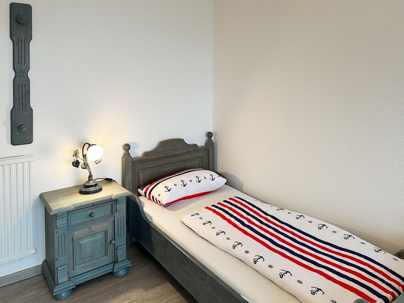 Ein Schlafzimmer mit einem Bett, Nachttisch und einer Lampe.