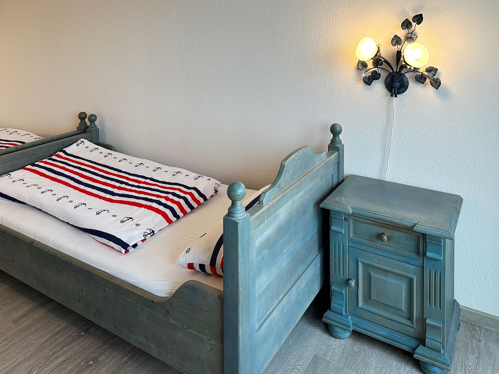 Schlafzimmer mit Bett, Nachttisch und Wandlampe.