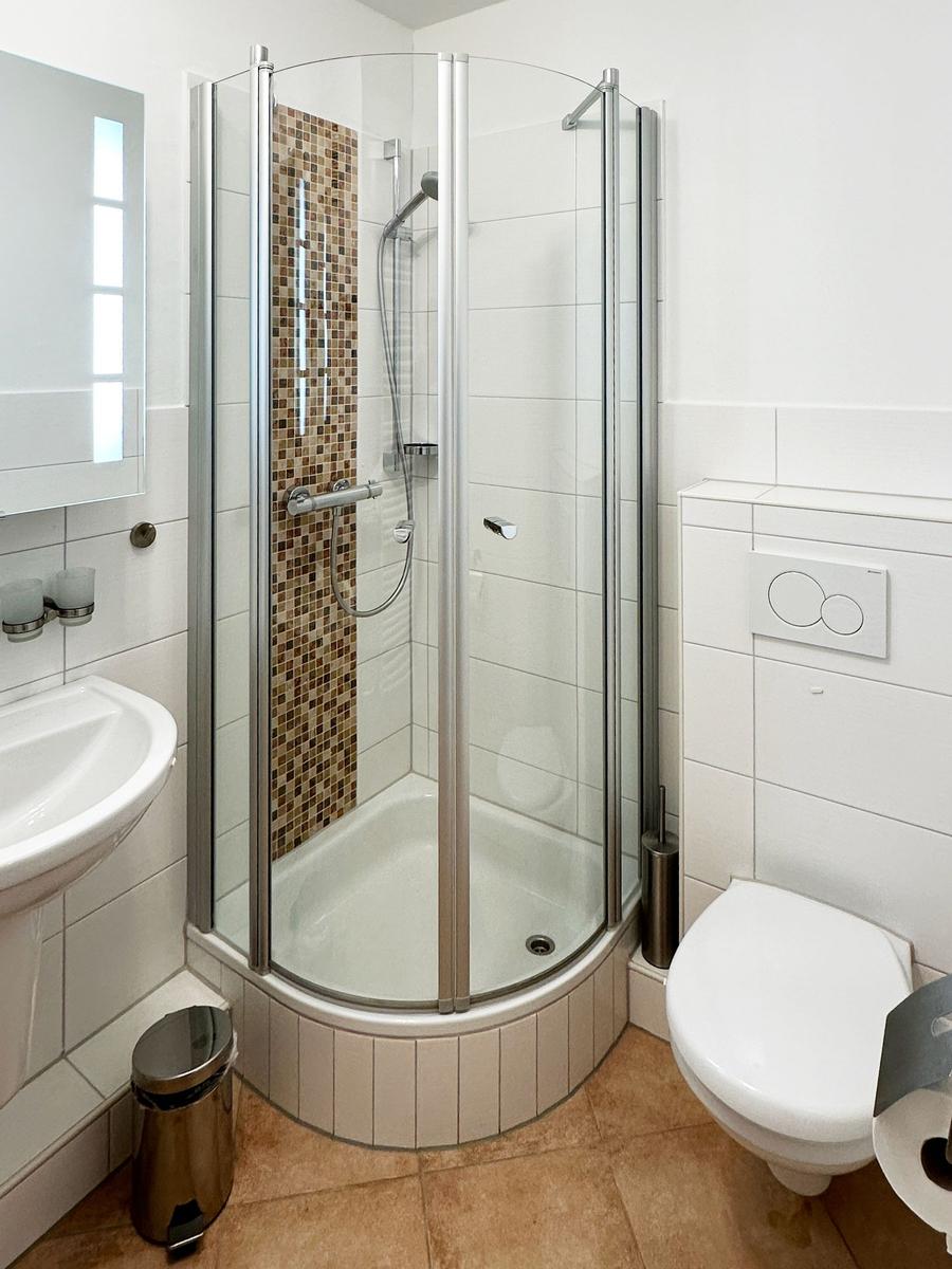 Badezimmer mit Dusche, Toilette und Waschbecken.