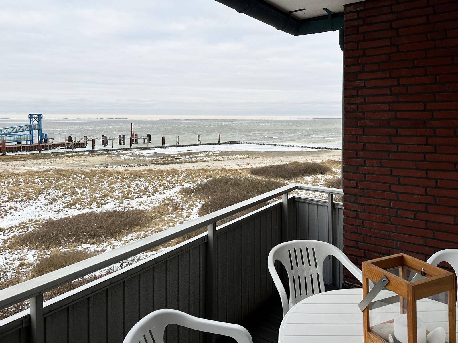 Terrasse mit Blick auf schneebedeckten Strand und Hafen.