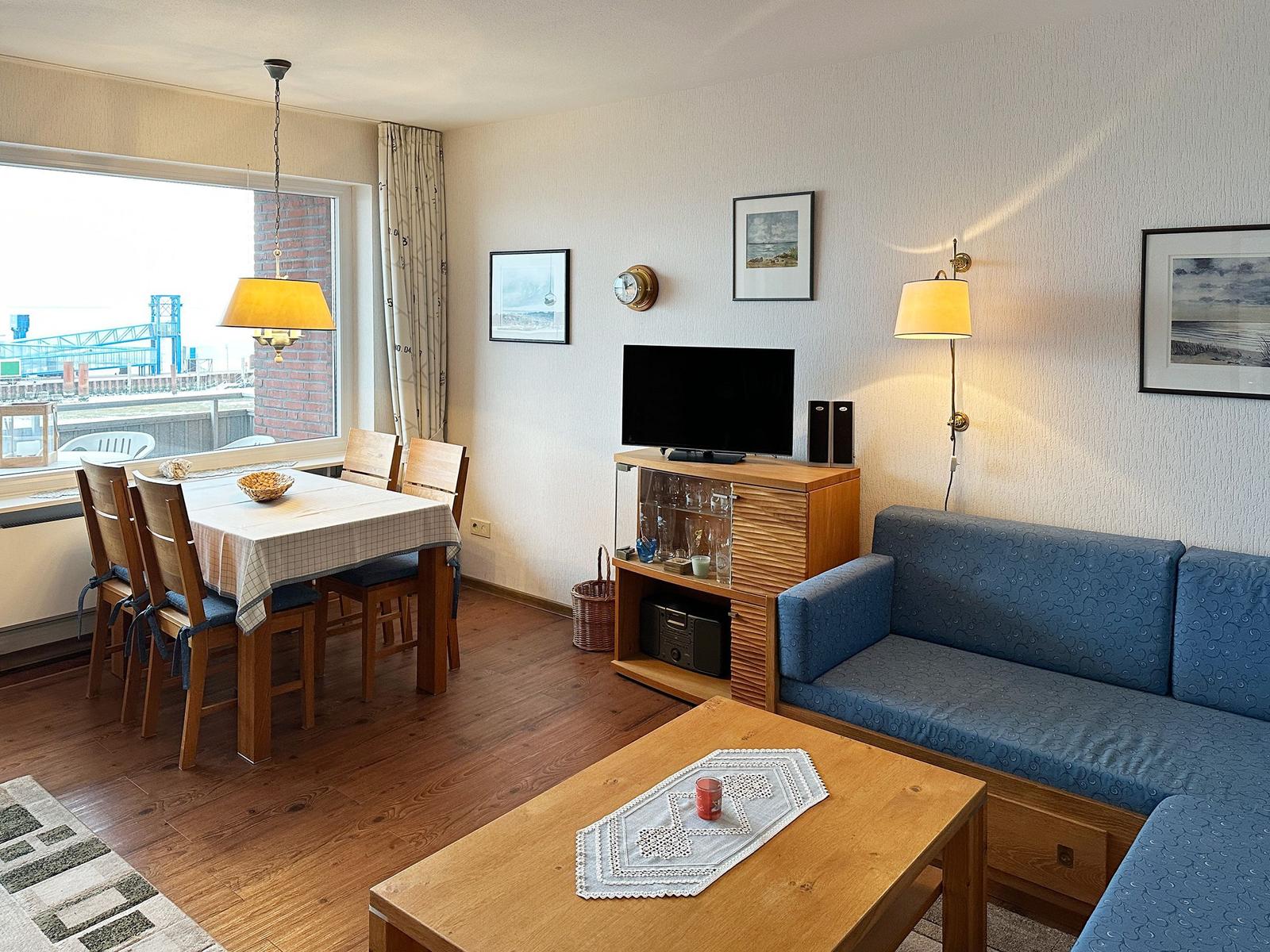 Wohnzimmer mit Sofa, Esstisch und TV. Blick auf Hafen.
