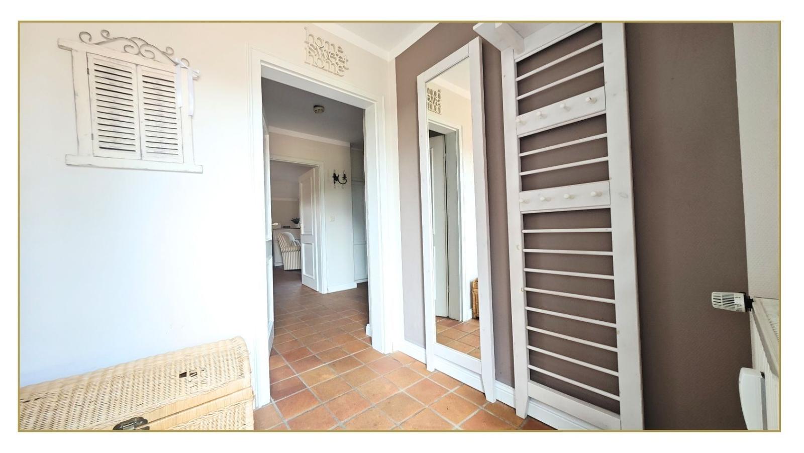 Eingangsbereich mit Flur, Spiegel und Garderobe. Terrakottaboden und Wanddekoration.