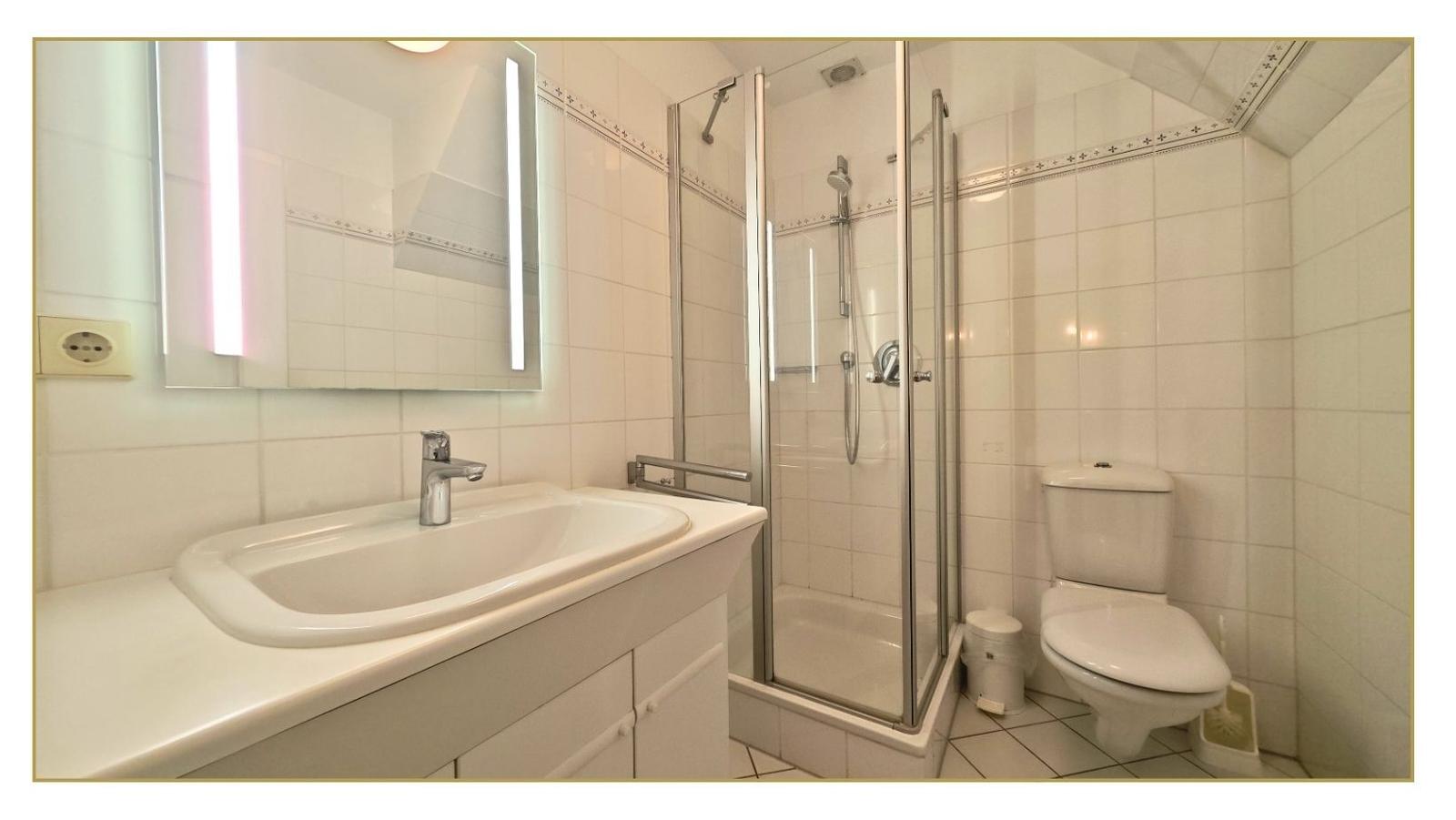 Badezimmer mit Dusche, Waschbecken und Toilette.