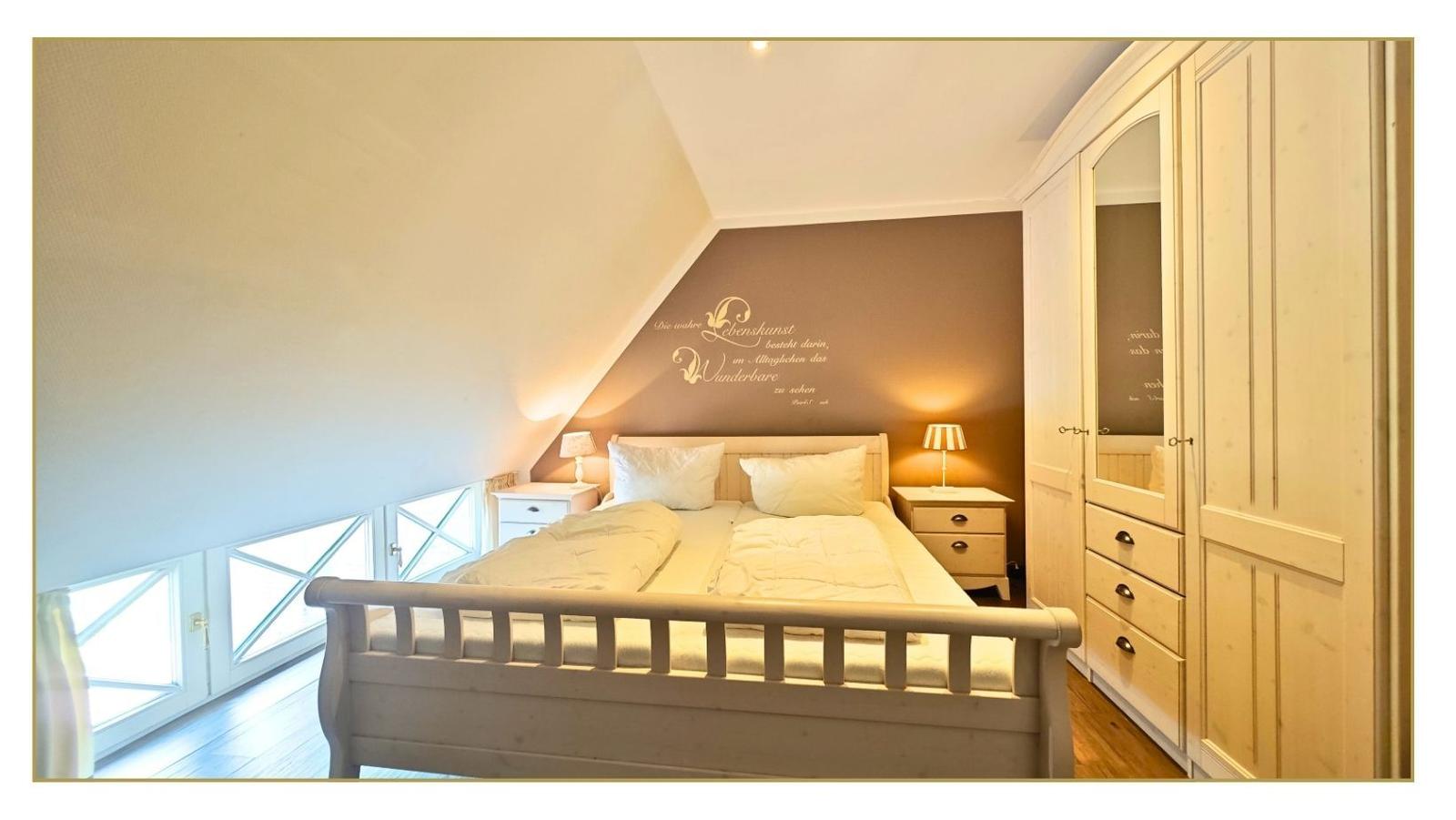 Schlafzimmer mit Dachschrägen, Bett, Nachttischen und Kleiderschrank.