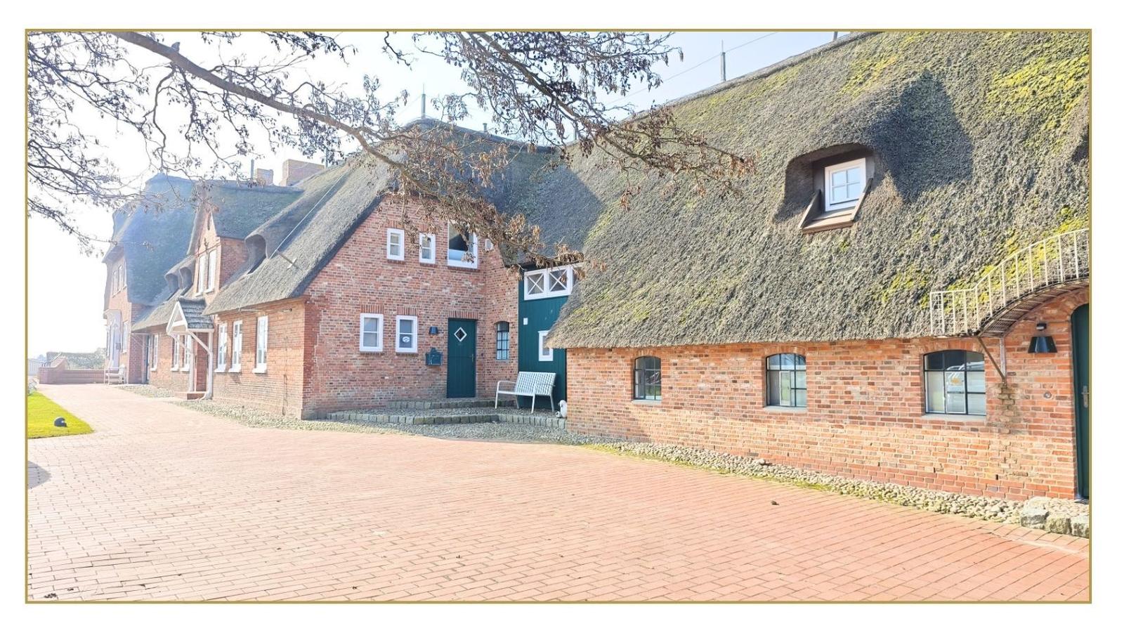 Roter Backsteinbau mit Strohdach und grüner Tür