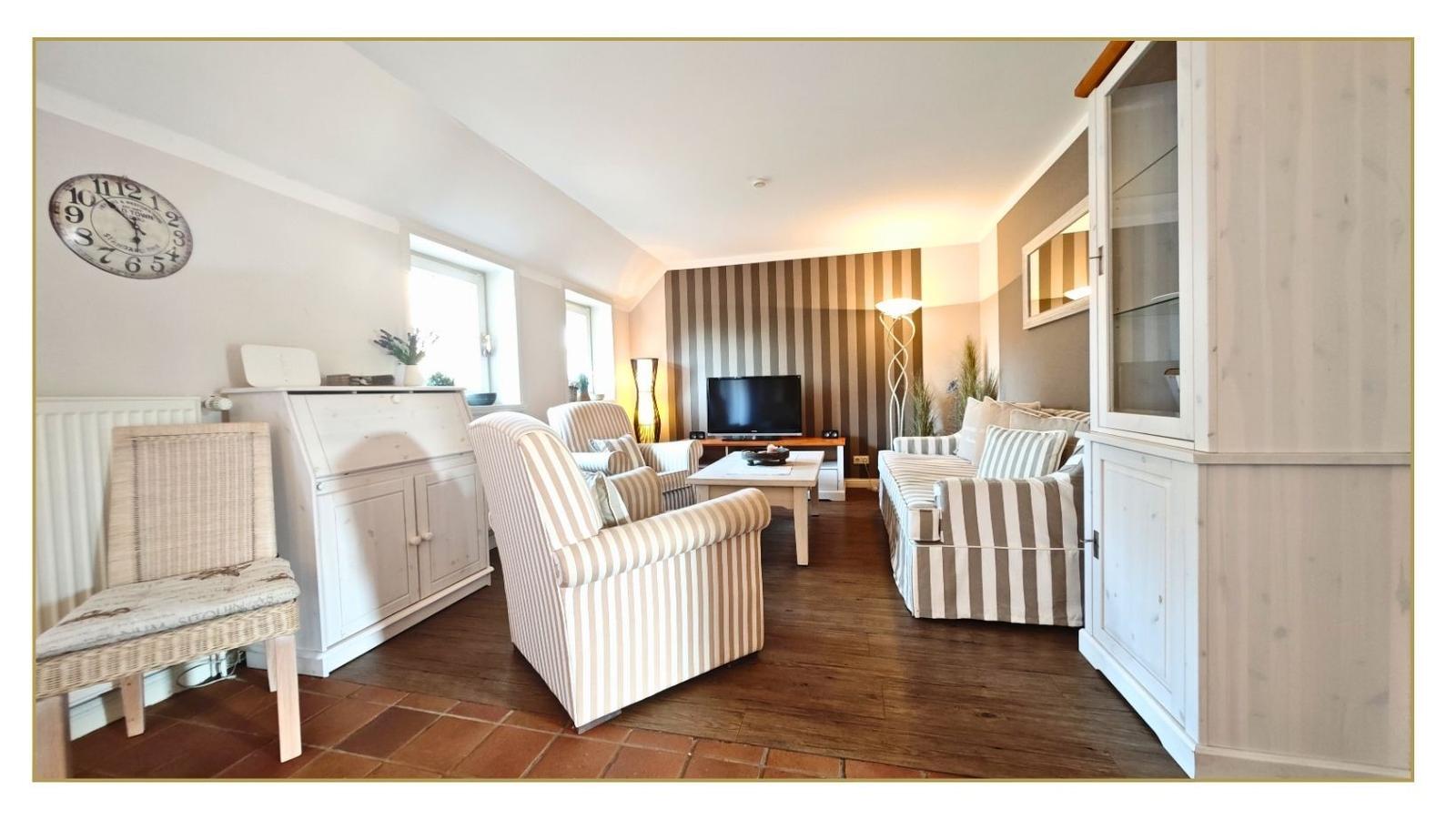 Wohnzimmer mit Sitzgruppe, Fernseher und Holzboden.