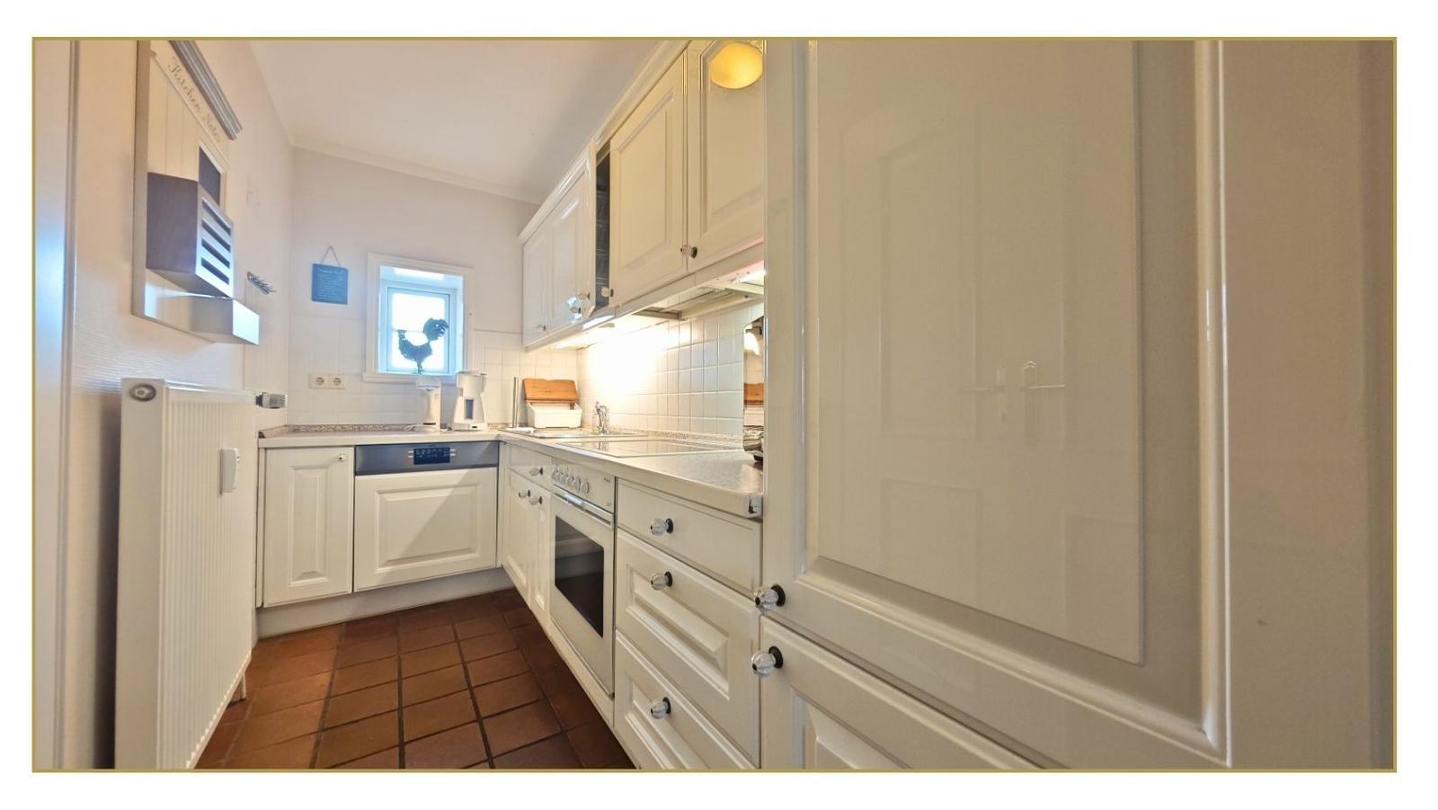 Küche mit weißen Schränken, Arbeitsplatte und Fenster.