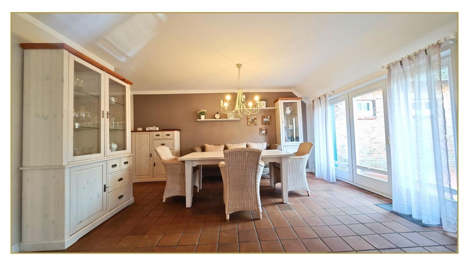 Esszimmer mit Esstisch, Stühlen und Schränken. Terrasse über Glastür.