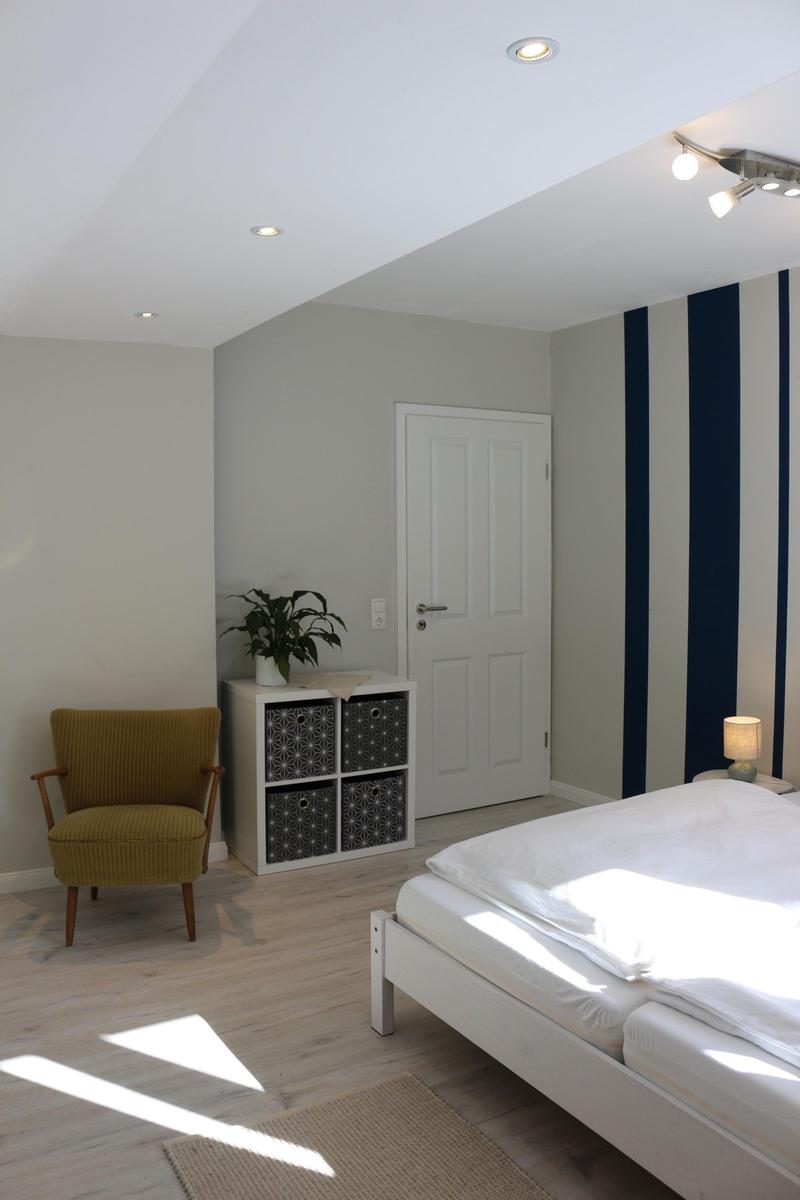 Schlafzimmer mit Bett, Stuhl und Regal an der Wand.