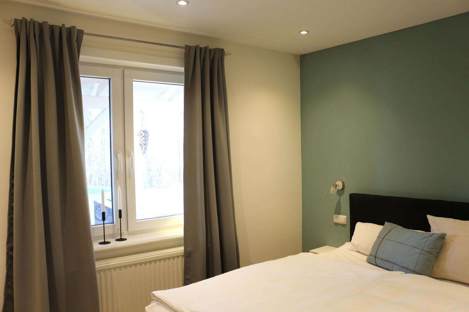 Schlafzimmer mit Bett, Fenster und grüner Wand
