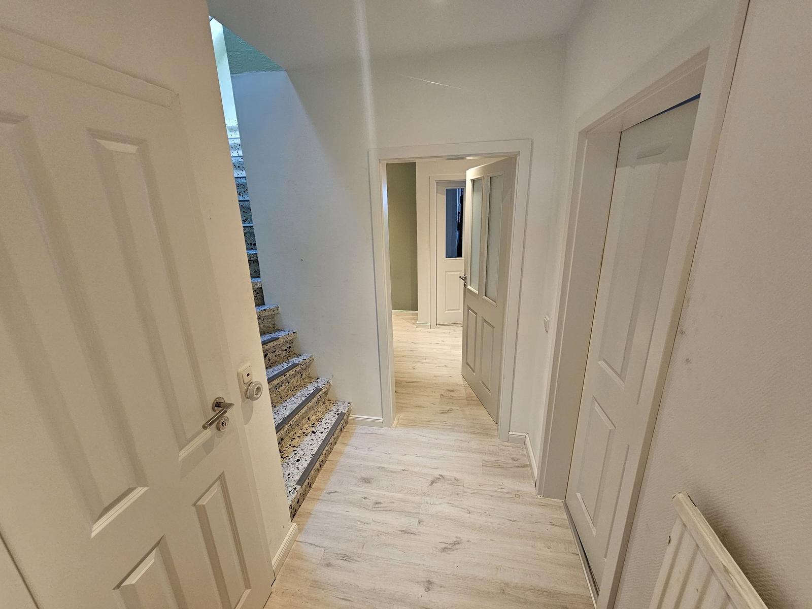 Flur mit Holzboden, Treppe und Türen zu verschiedenen Räumen.
