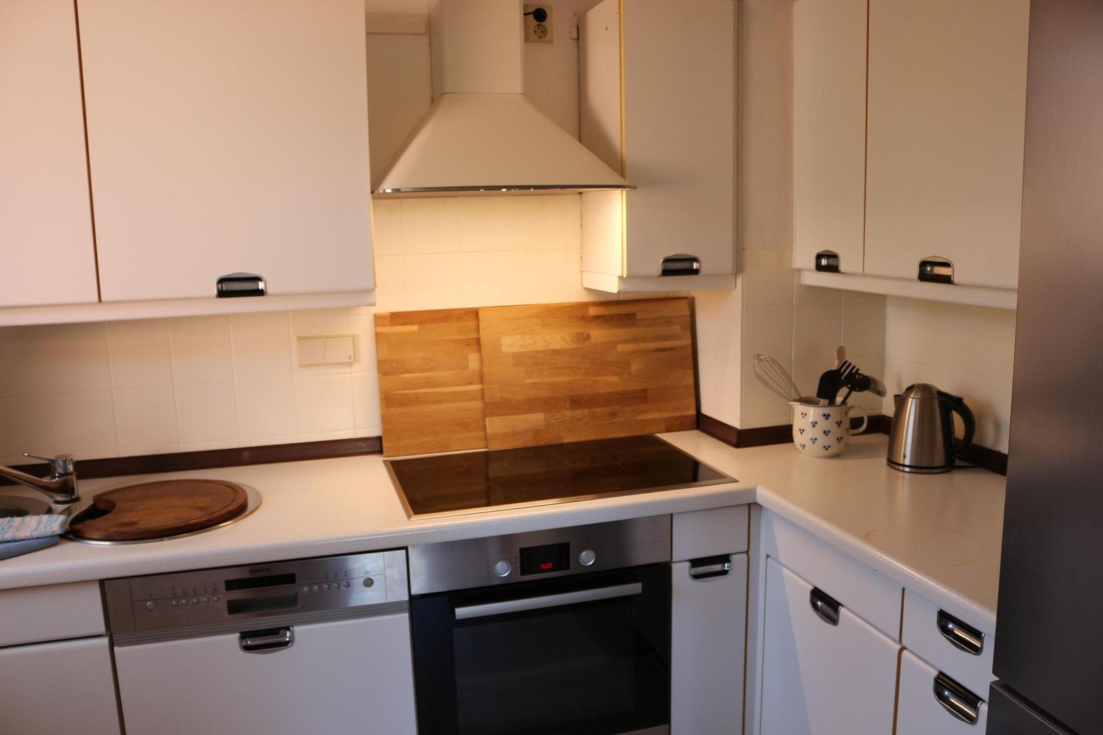 Küche mit Induktionskochfeld, Backofen und Spülmaschine.