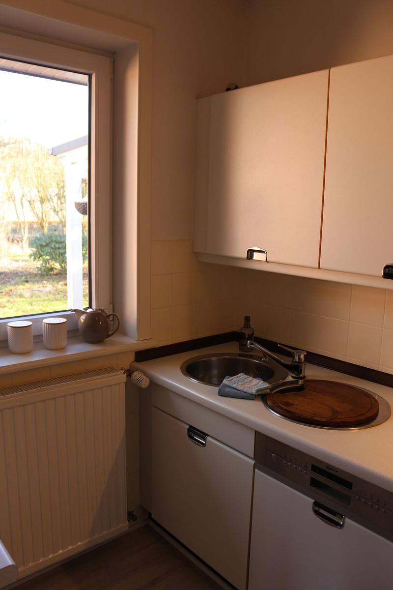 Küche mit Spüle, Waschmaschine und Fenster zum Garten