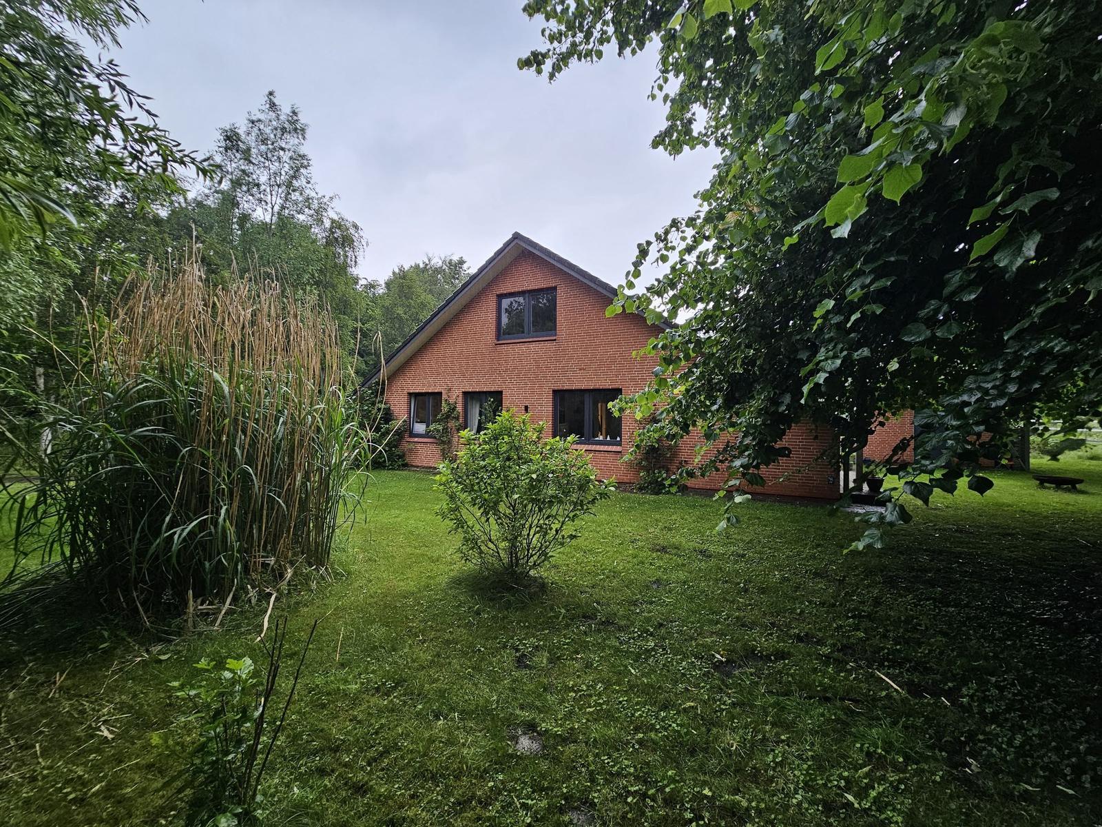 Rotes Backsteingebäude mit Garten und Bäumen.