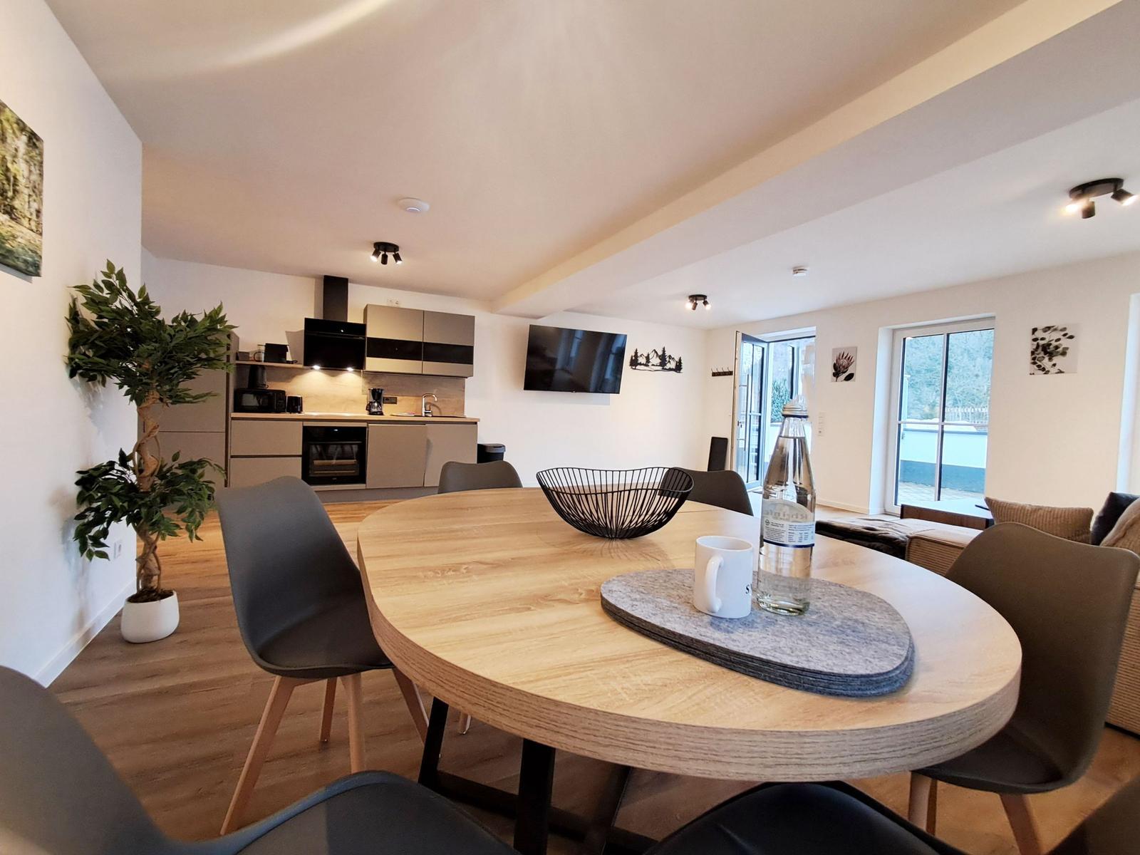 Essbereich mit Holztisch, Stühlen und Blick in die Küche.