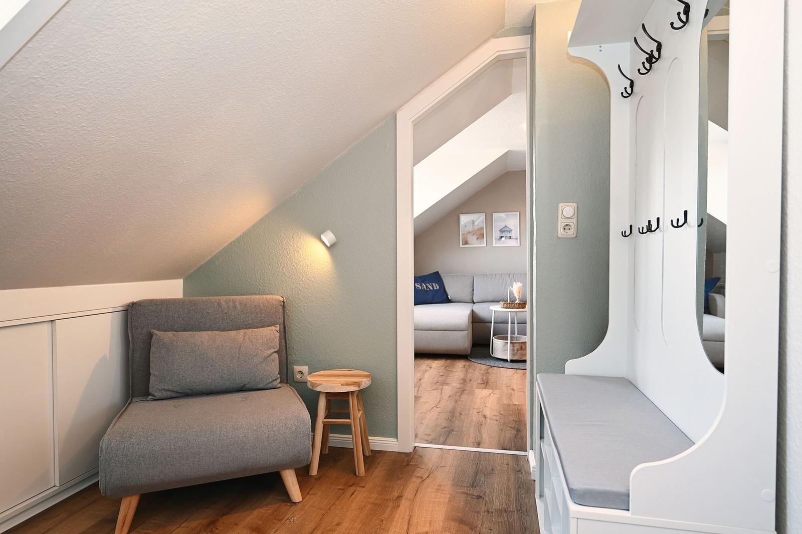 Eingangsbereich mit Kleiderschrank und Sitzbank. Durchgang zu Wohnzimmer mit Sofa.