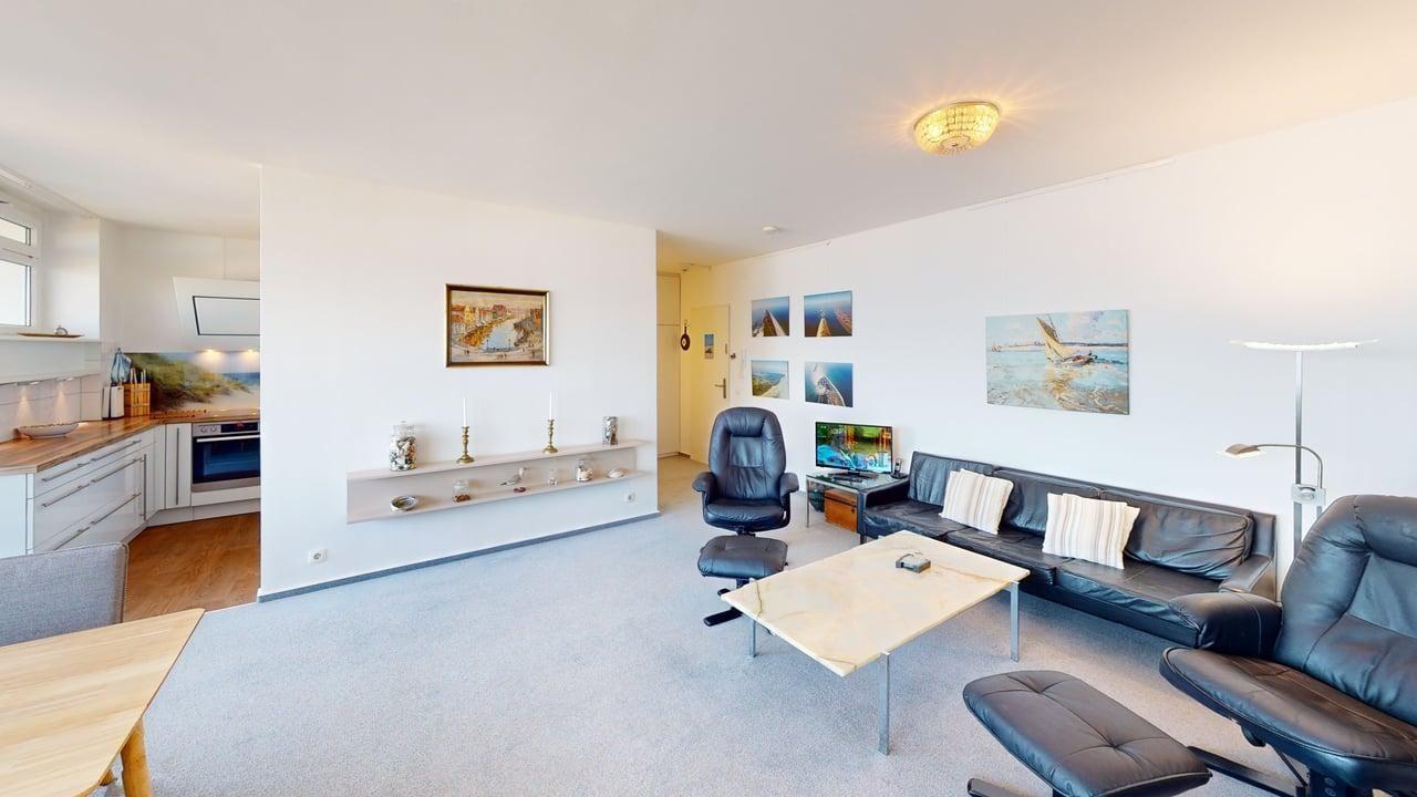 Wohnzimmer mit Ledersofa, Schreibtisch und Küchenbereich.