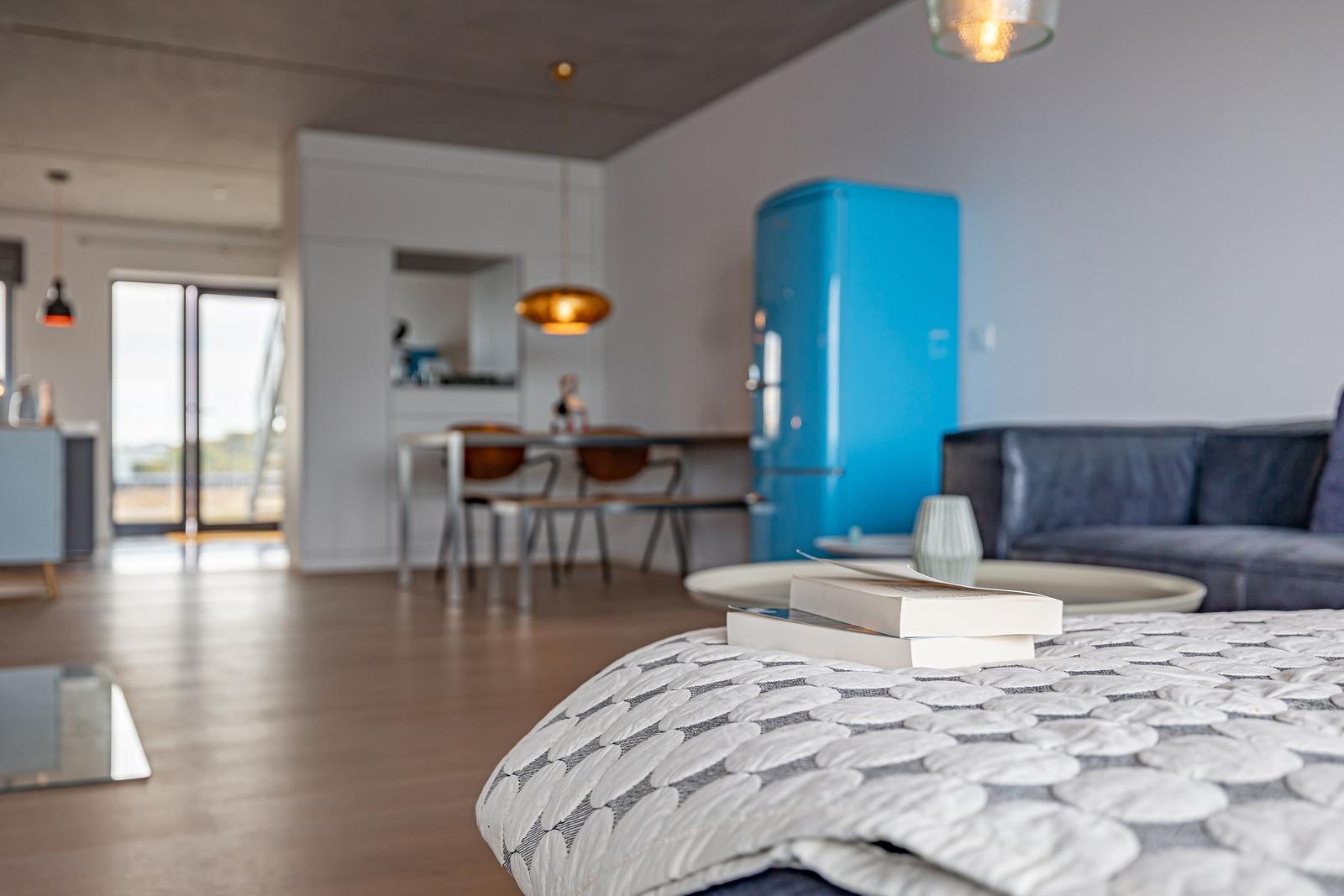 Ein Schlafzimmer mit Blick auf Wohnbereich und Küchenbereich mit blauem Kühlschrank.