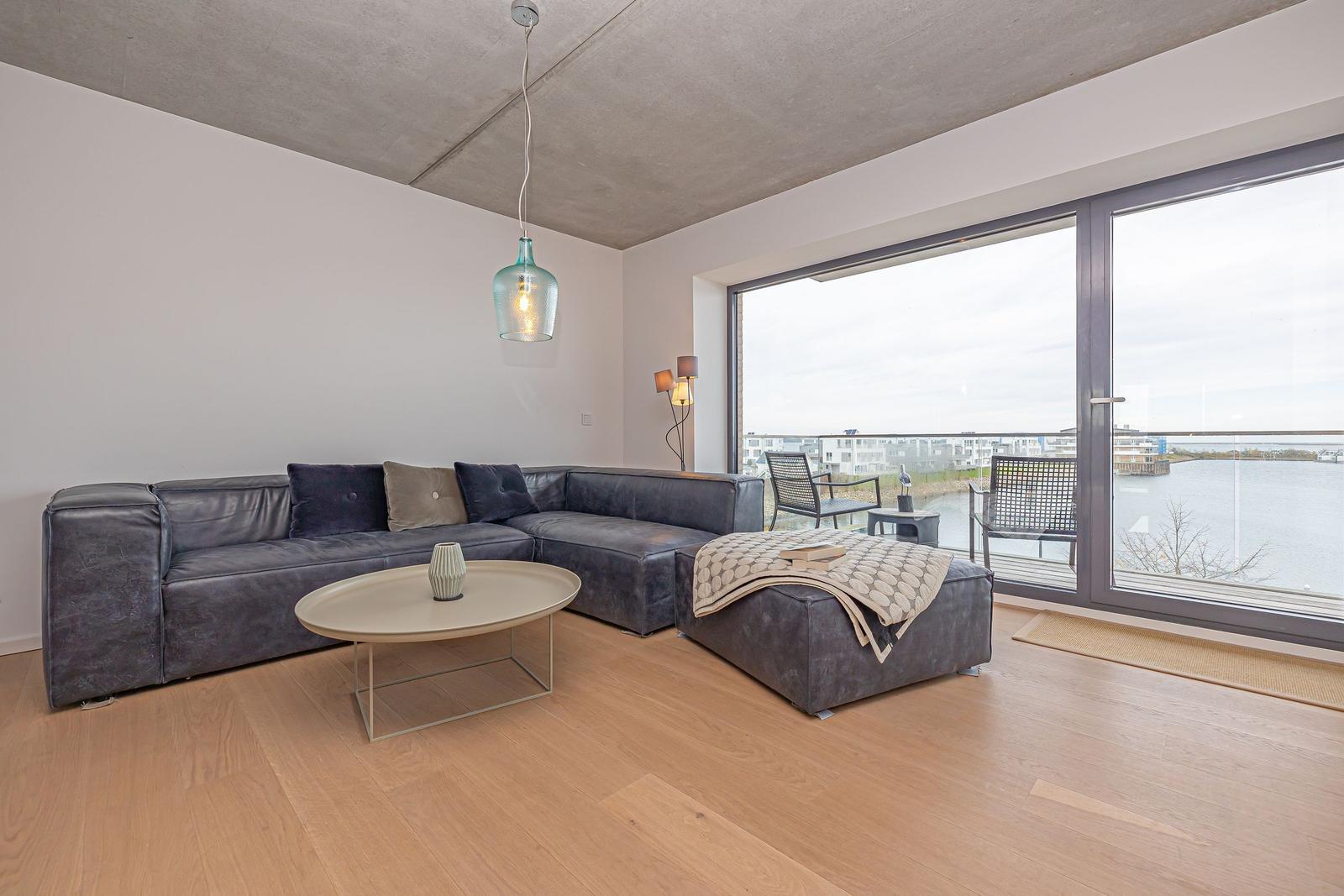 Wohnzimmer mit Sofa, Couchtisch und Blick auf Wasser