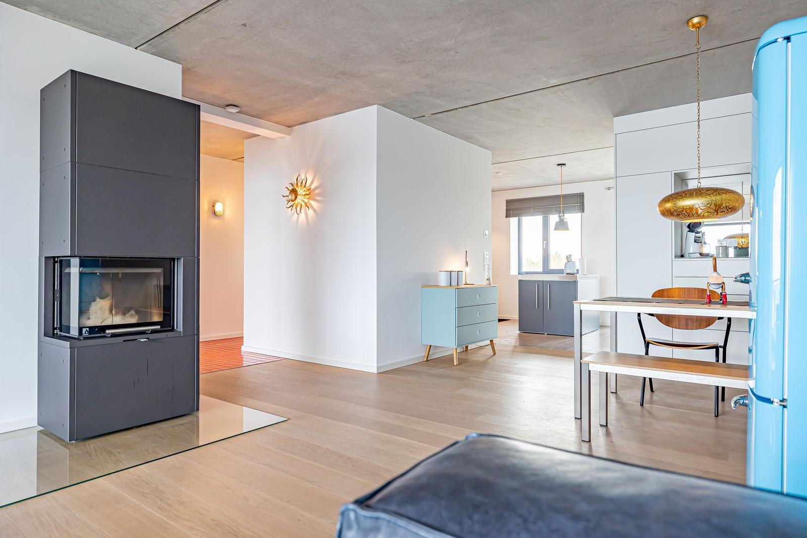 Wohnbereich mit Kamin, Esstisch und Küchenzeile.