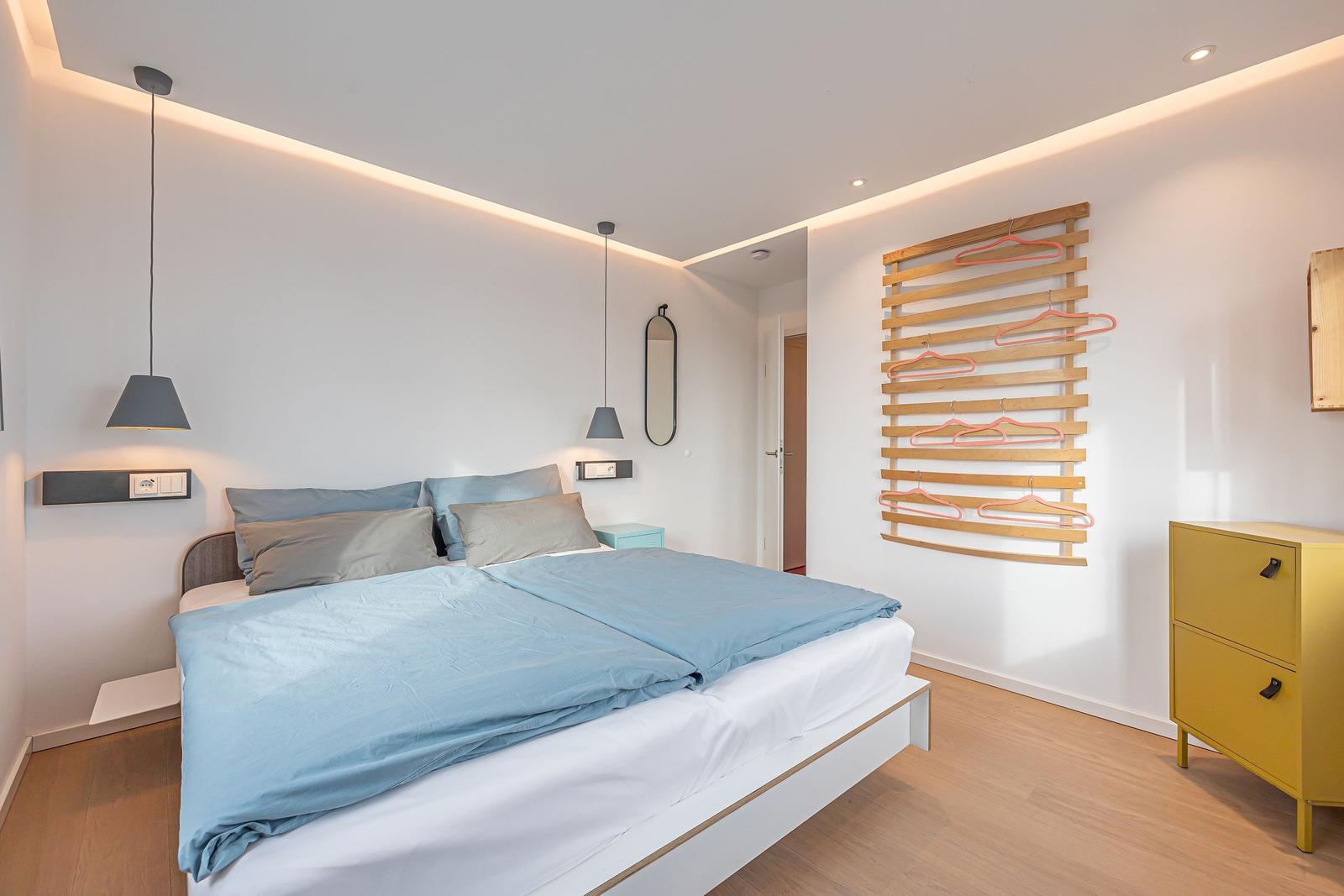 Schlafzimmer mit Bett, Kleiderständer und Schrank.