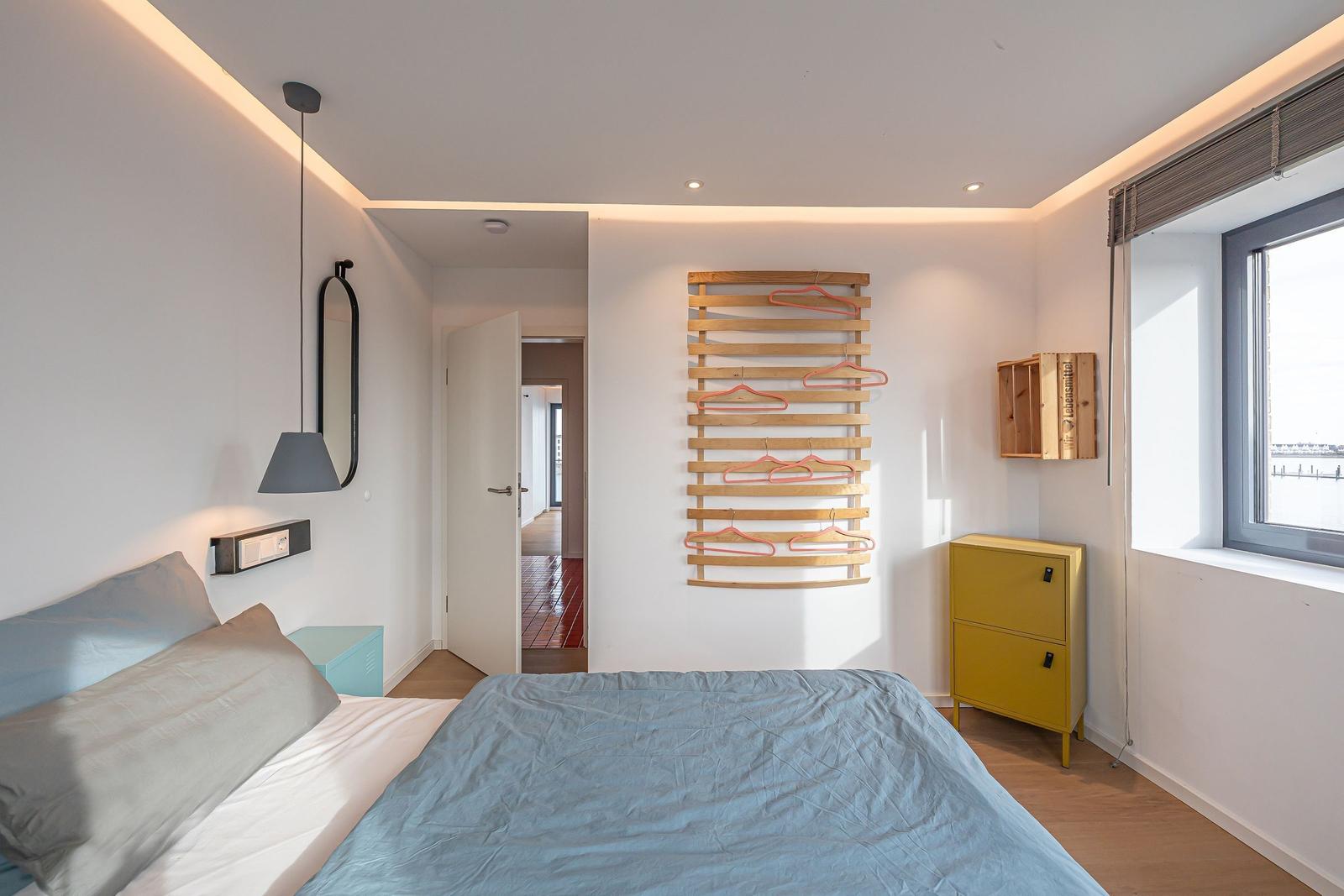 Schlafzimmer mit Bett, Kleiderständer und Fenster