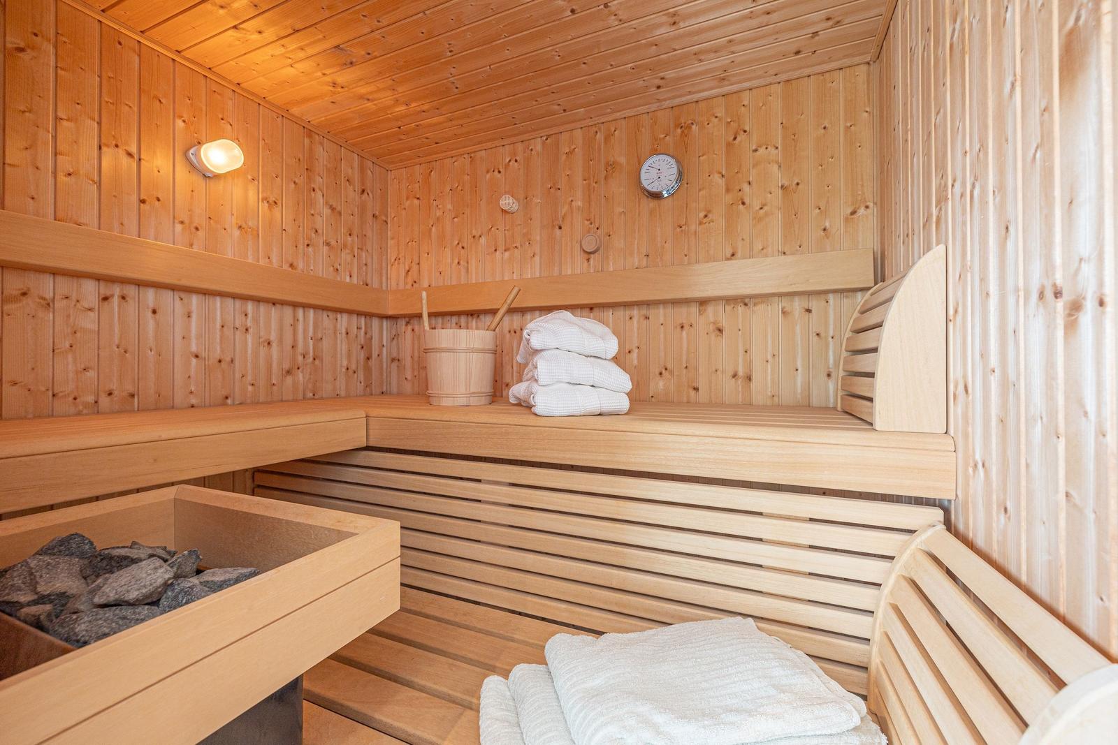 Holzsauna mit Banken, Handtuchstapel und Steinofen.