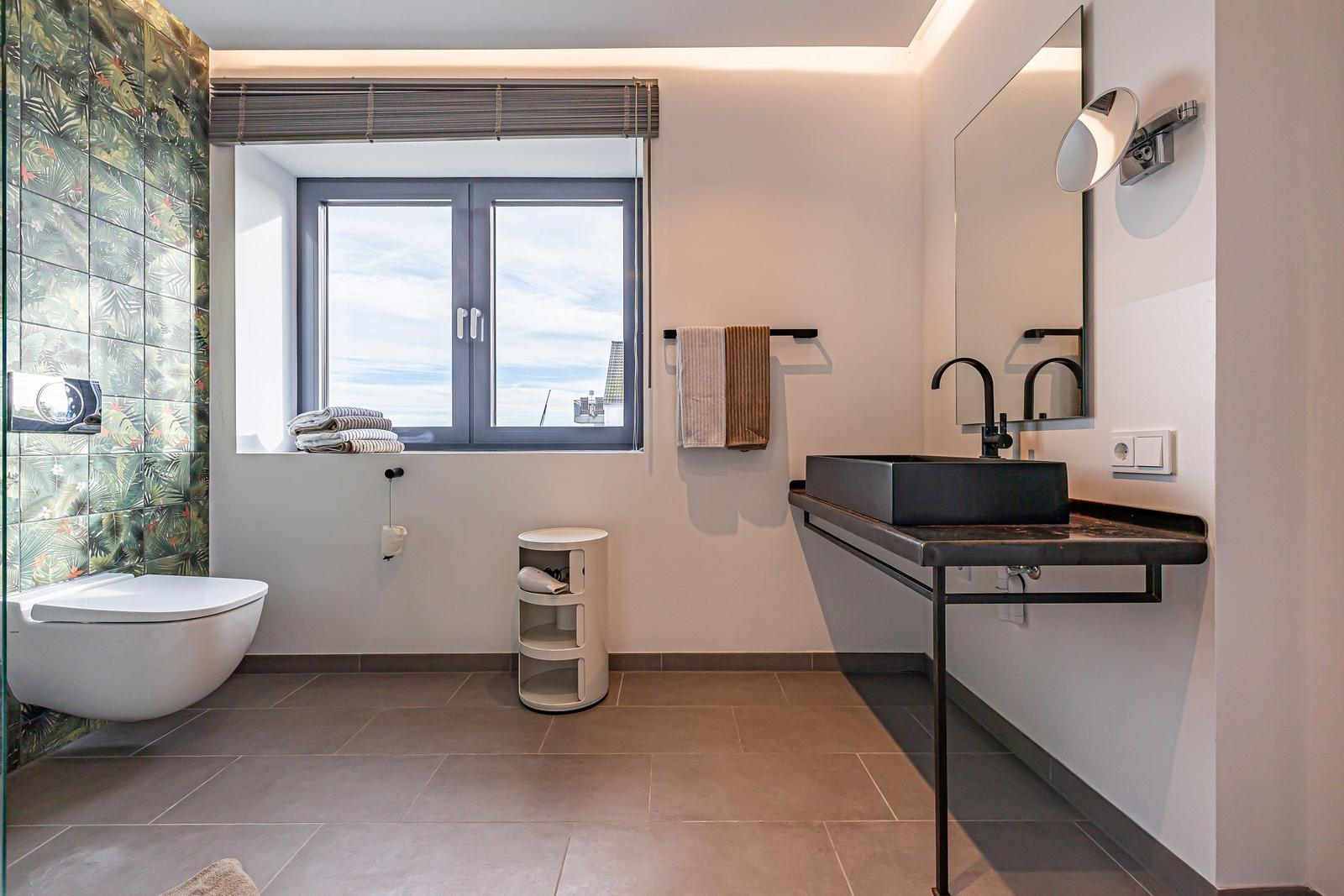 Badezimmer mit Dusche, Waschbecken und Fenster mit Blick.