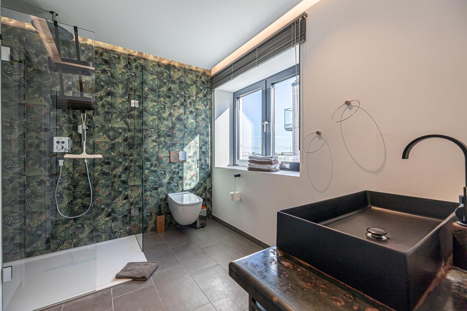 Badezimmer mit Dusche, Waschbecken und Fenster