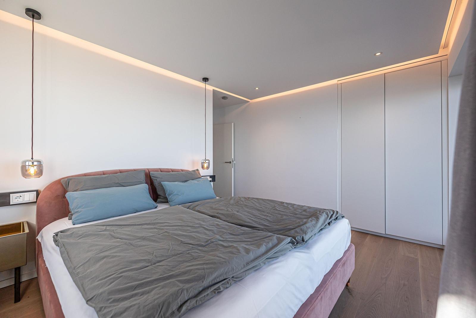 Schlafzimmer mit Bett, Kleiderschrank und Hängelampen.