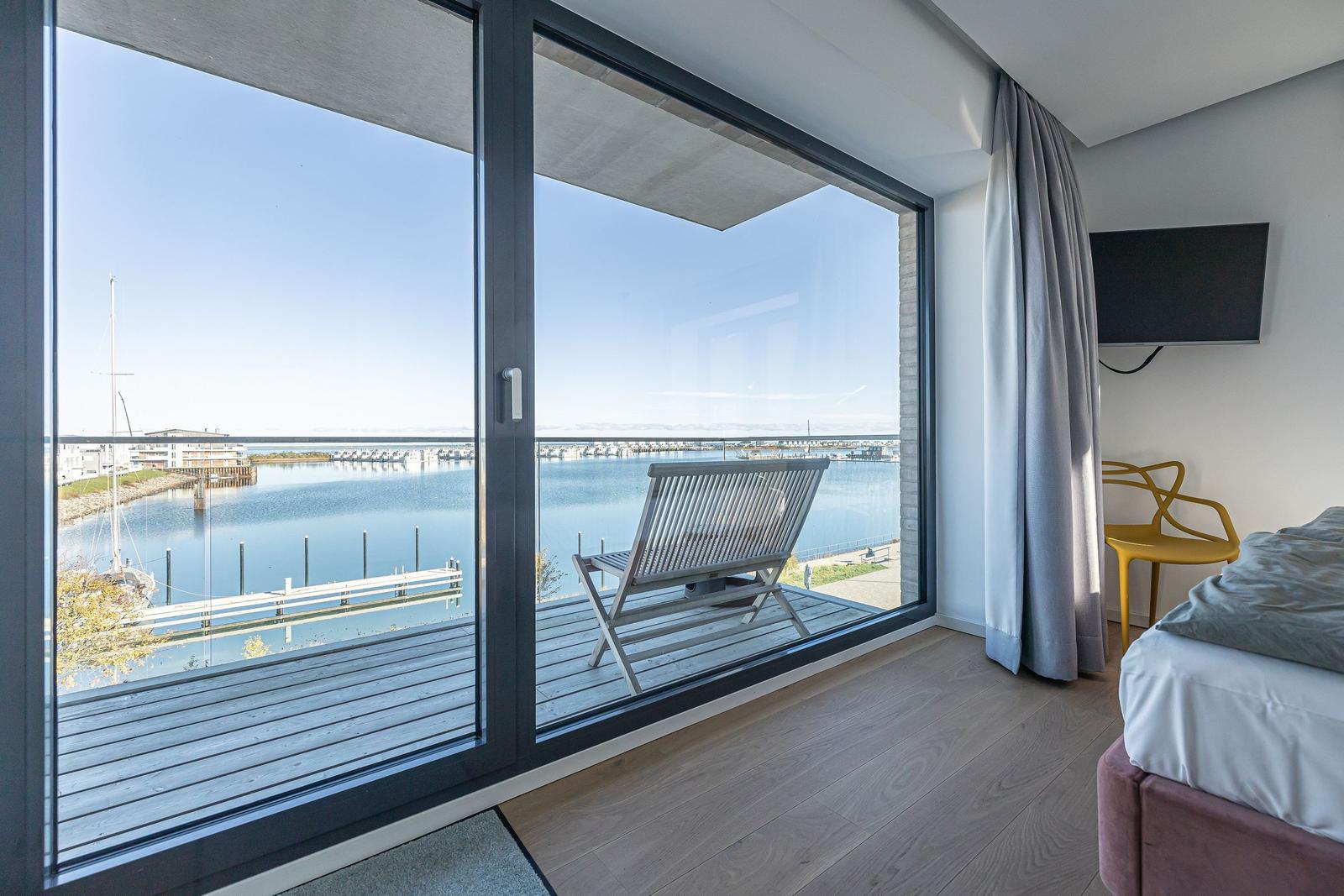 Zimmer mit Blick auf Hafen und Bootshäfen über große Glastüren.
