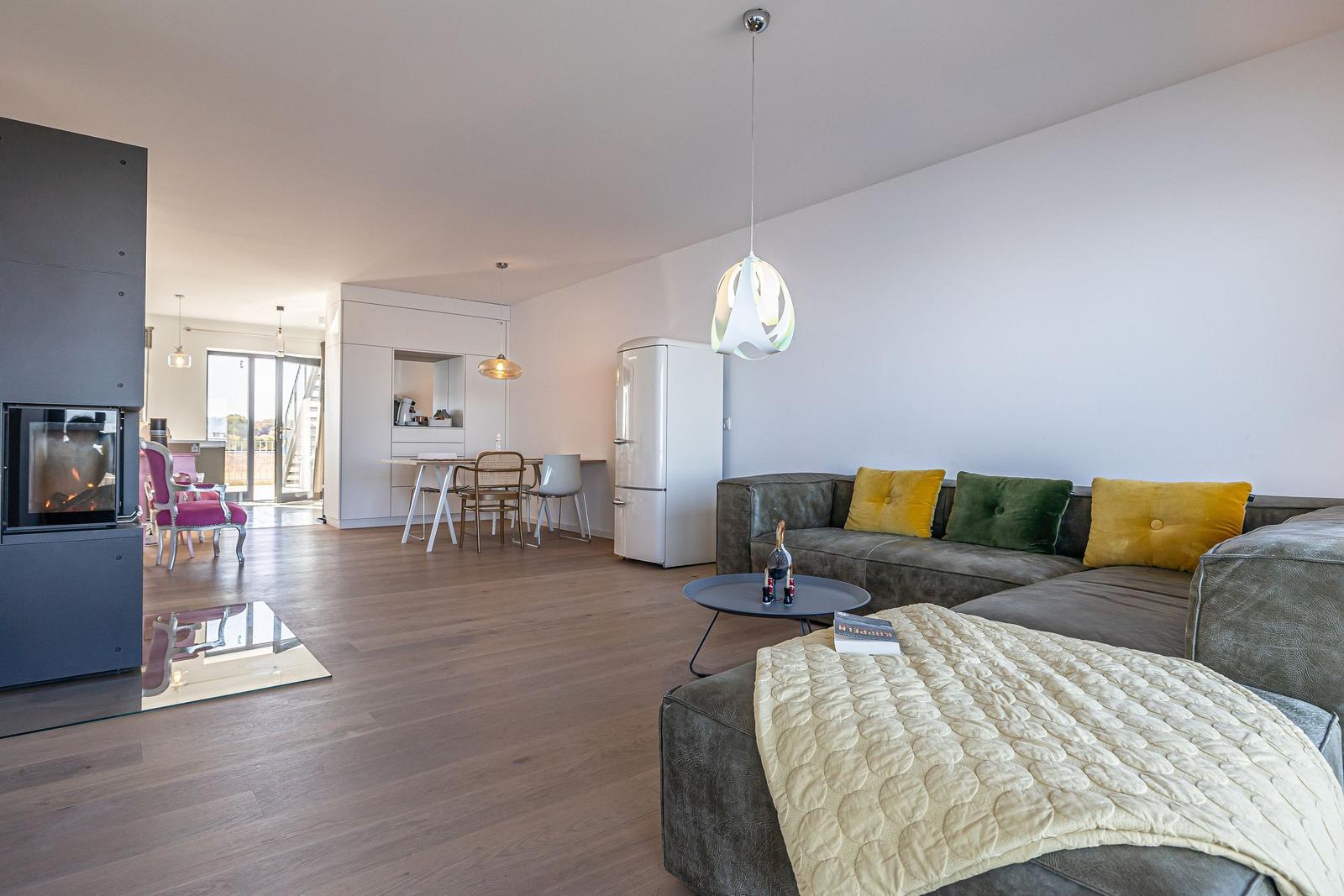 Wohnbereich mit Sofa, Kamin und Essbereich im Hintergrund.