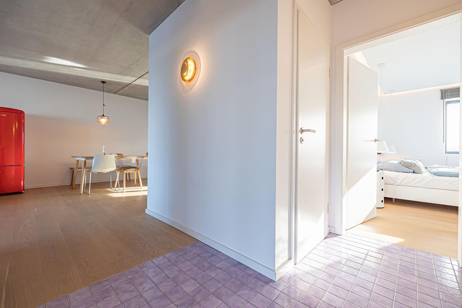 Eingangsbereich mit Tür zur Schlafzimmer. Im Hintergrund Küche mit rotem Kühlschrank.