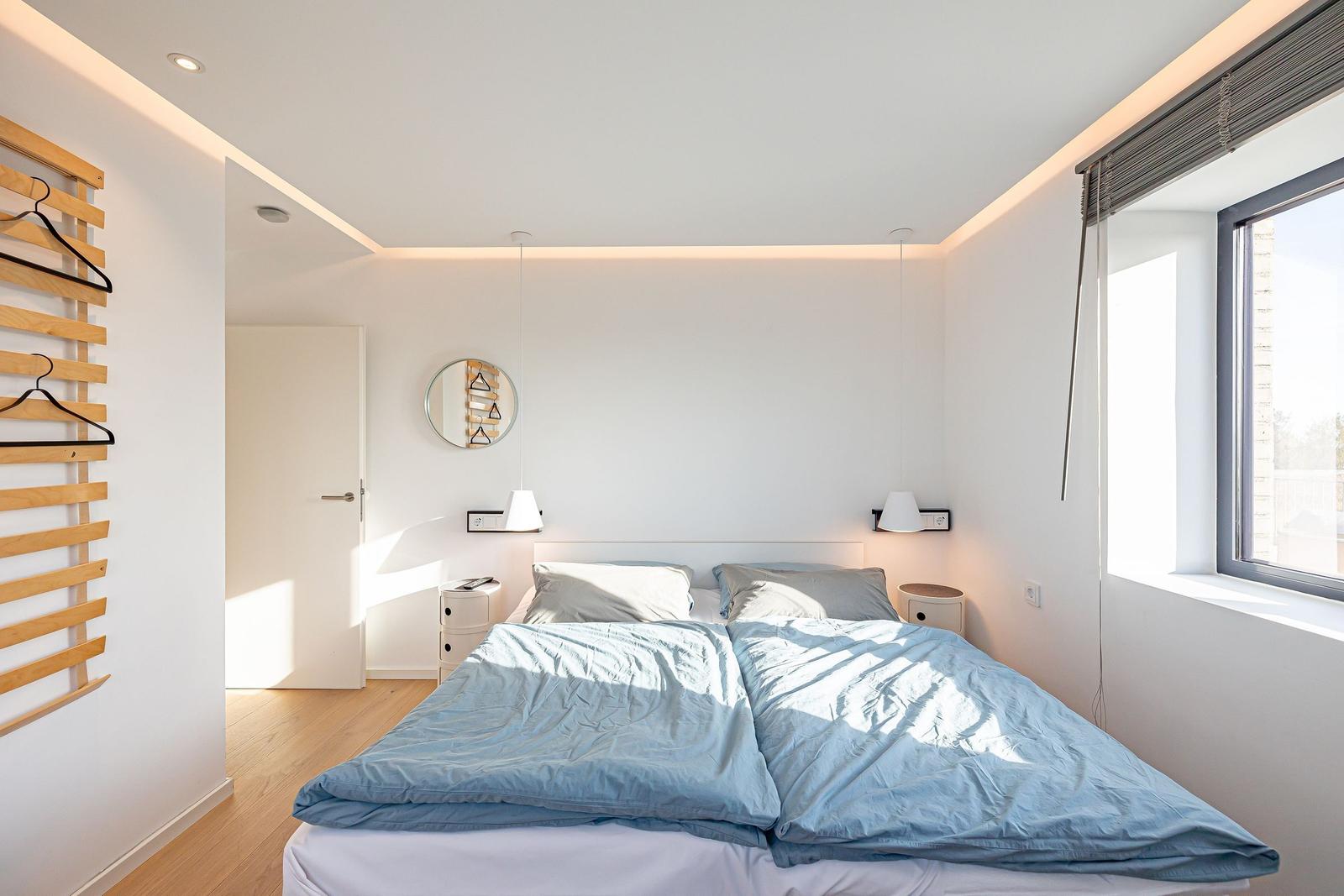 Schlafzimmer mit Bett, Fenster und Kleiderständer