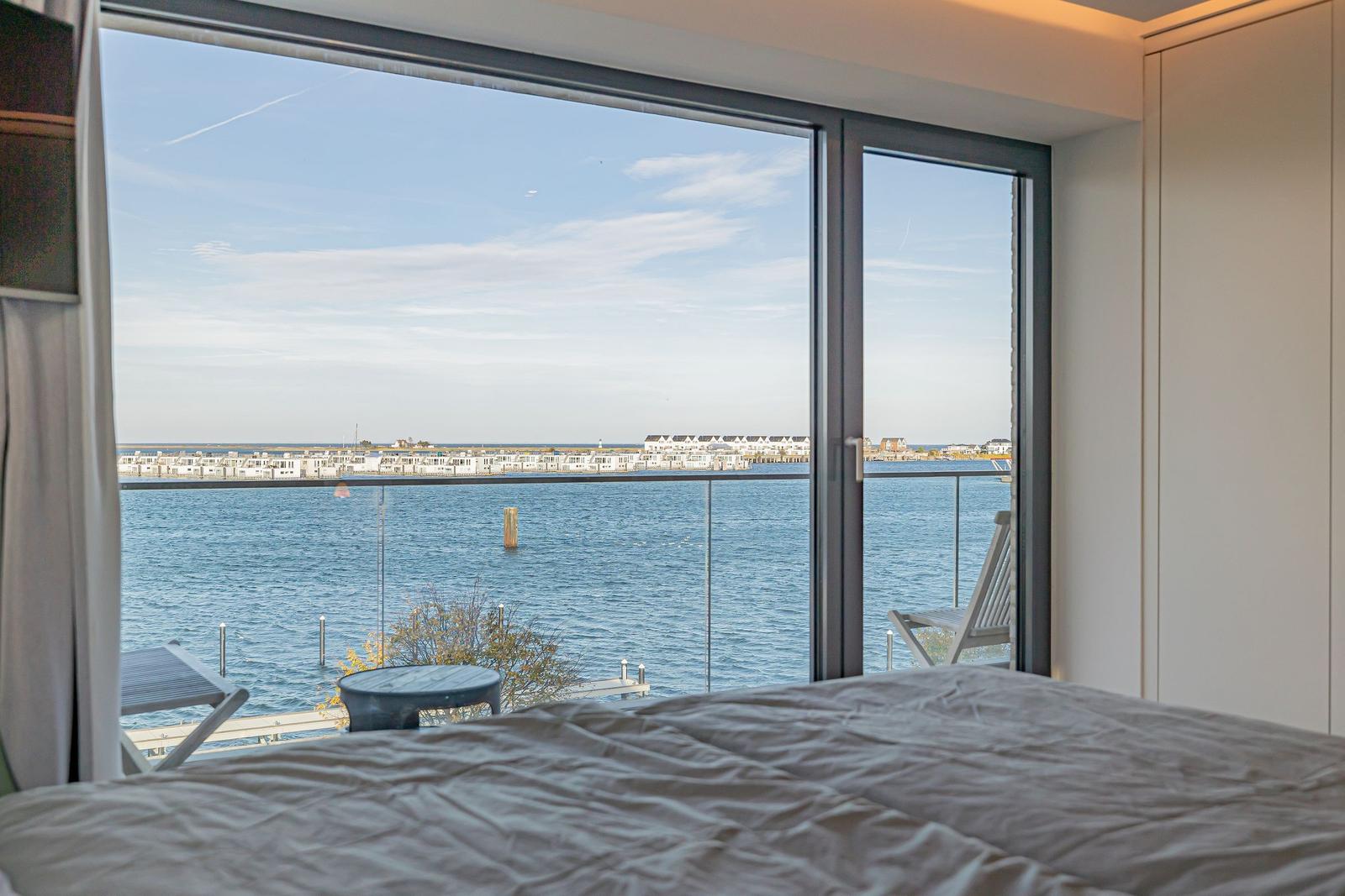 Schlafzimmer mit Blick aufs Wasser und Terrasse mit Stuhl.