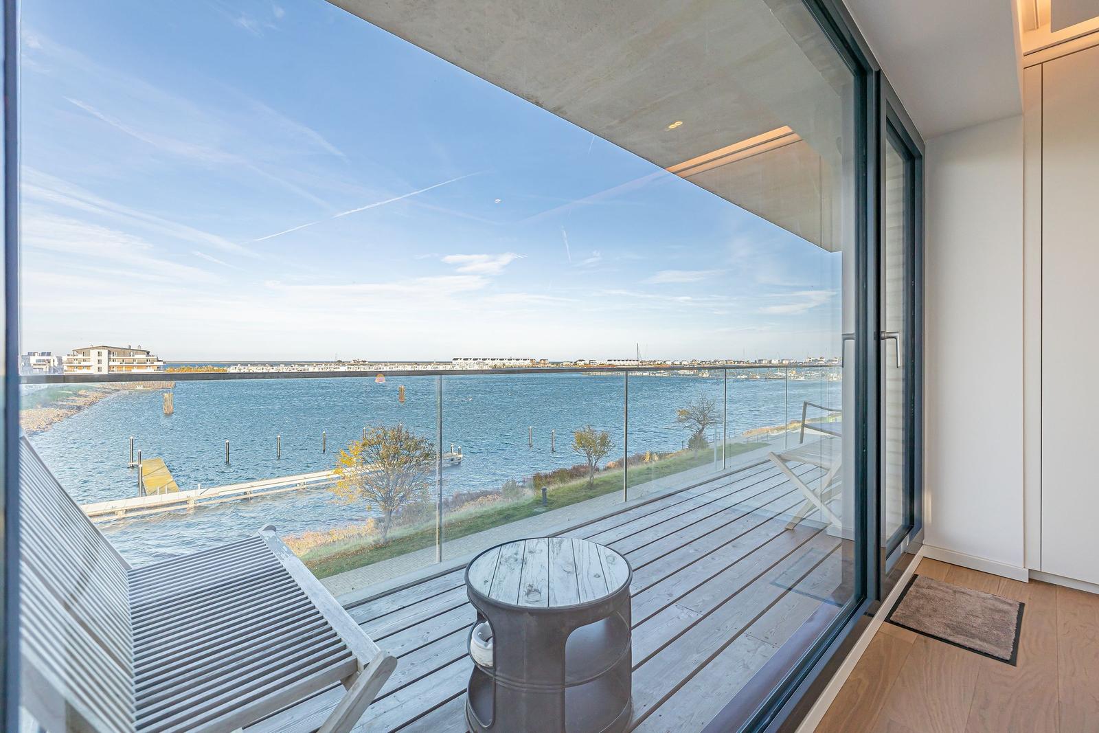 Terrasse mit Sitzgelegenheit und Blick auf Wasser und Ufer.