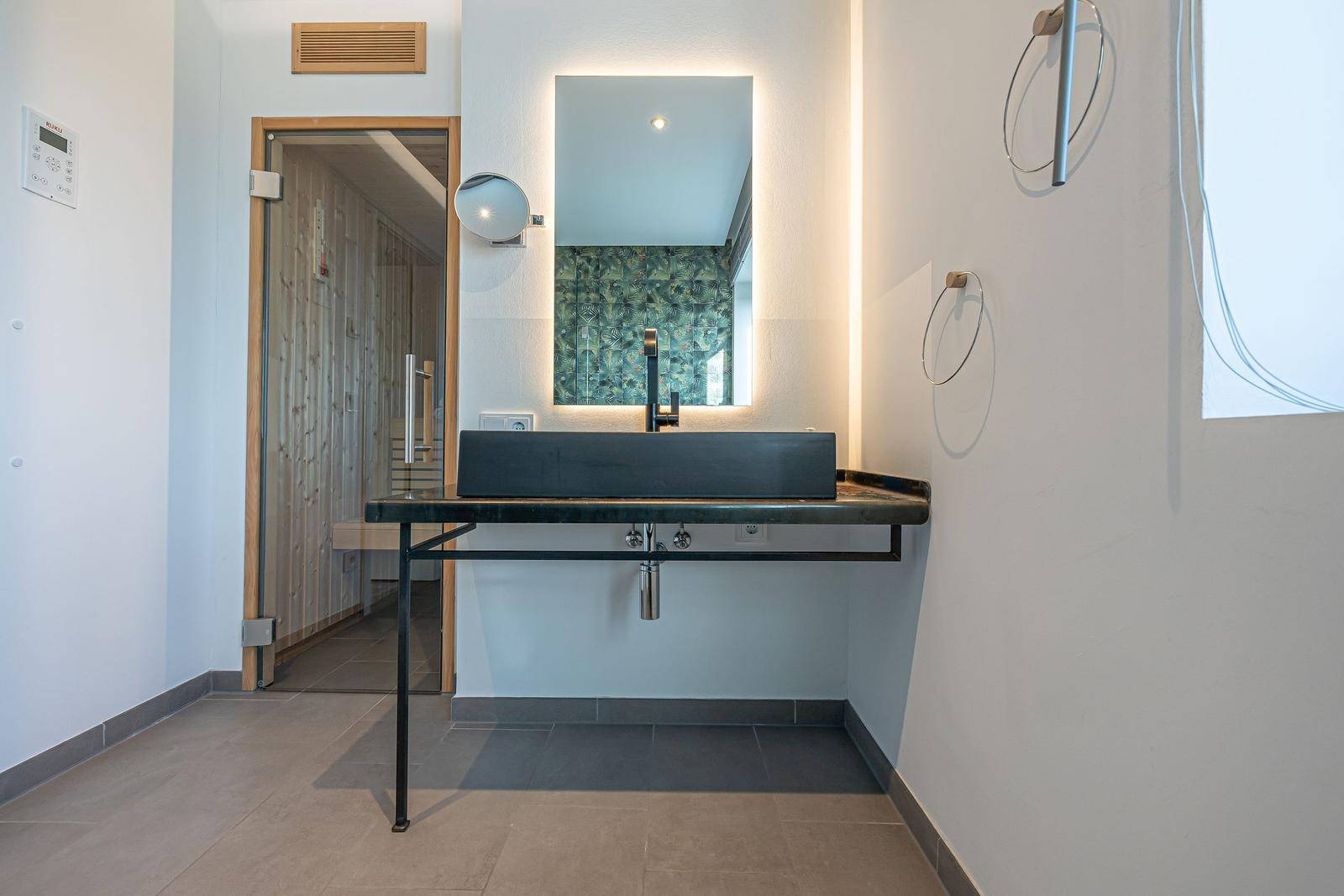 Waschbecken mit Spiegel und Handtuchhalter in moderner Badezimmerausstattung.
