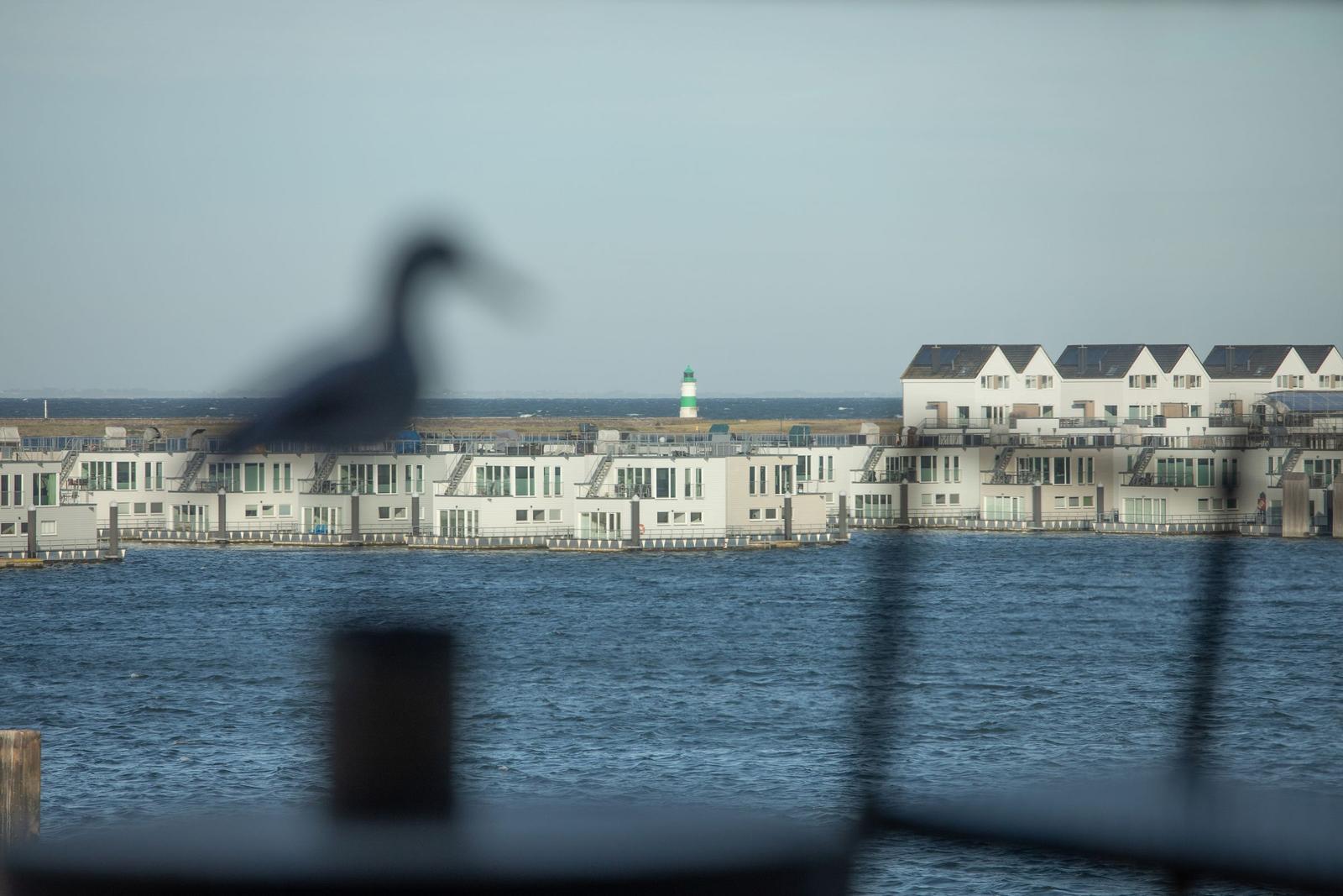 Wohnungen am Wasser mit Leuchtturm im Hintergrund