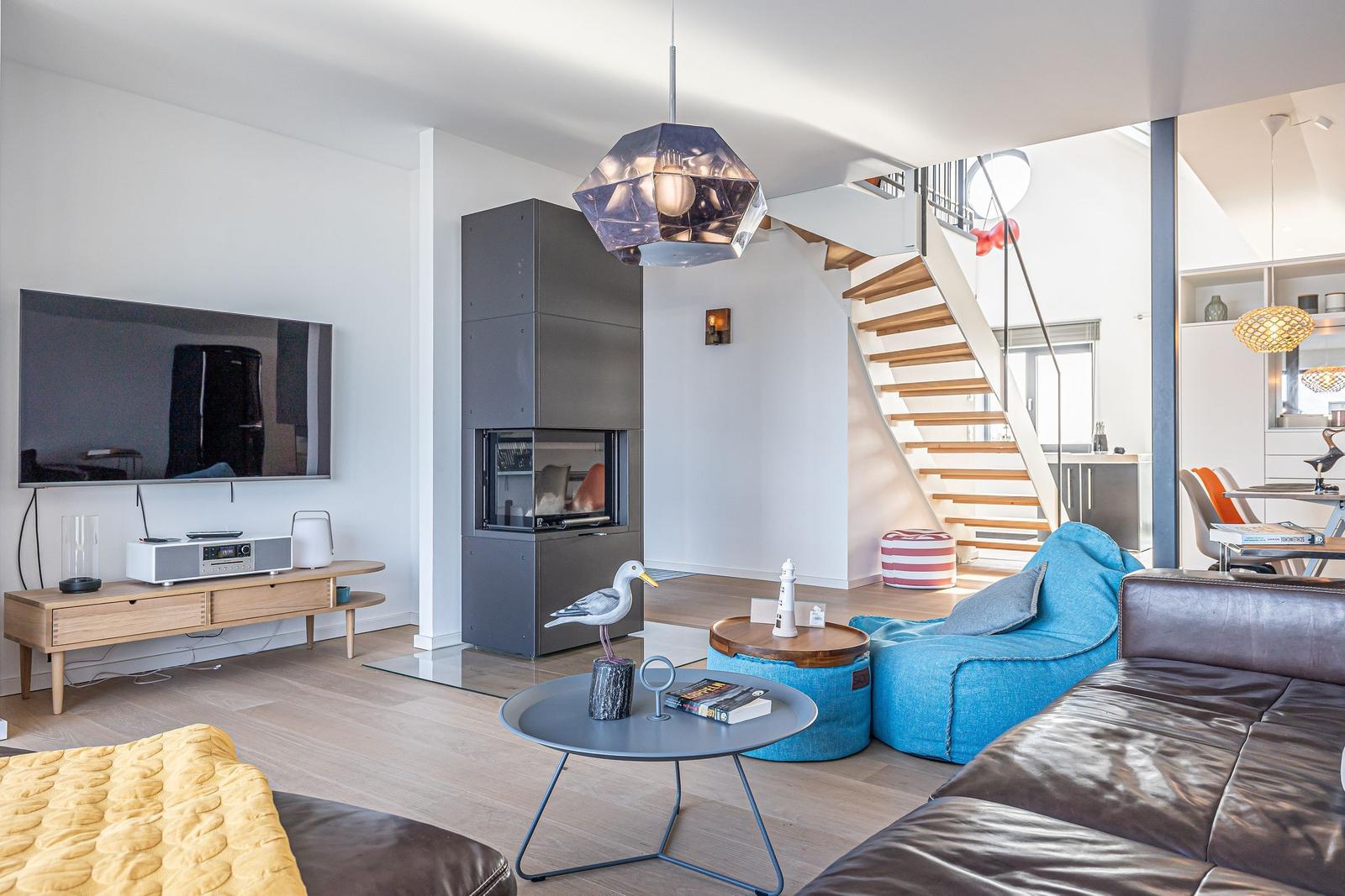 Wohnzimmer mit TV, Kamin und blauem Sitzmöbel