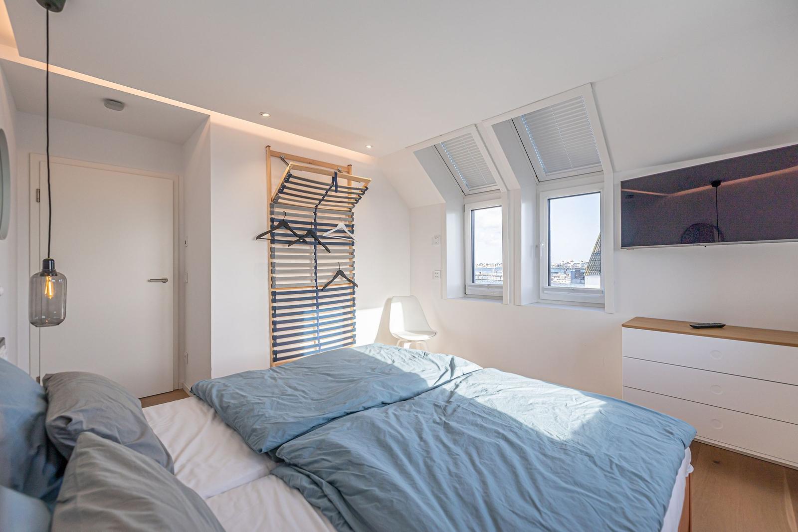 Schlafzimmer mit Dachfenster, Bett und Kleiderschrank.