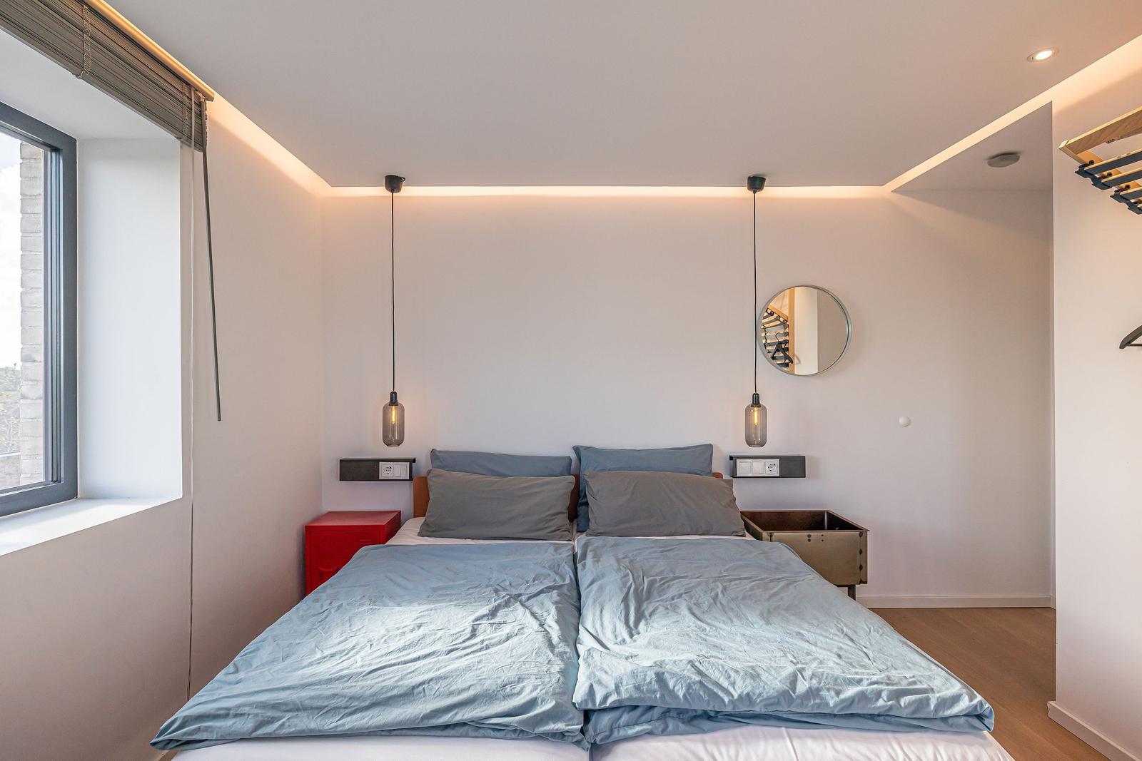 Schlafzimmer mit Doppelbett, Fenster und zwei Hängelampen.