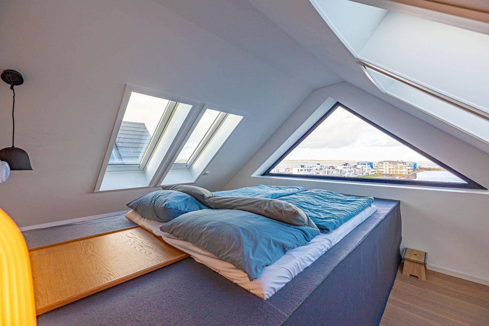 Schlafzimmer mit Dachfenstern und Blick auf die Umgebung.