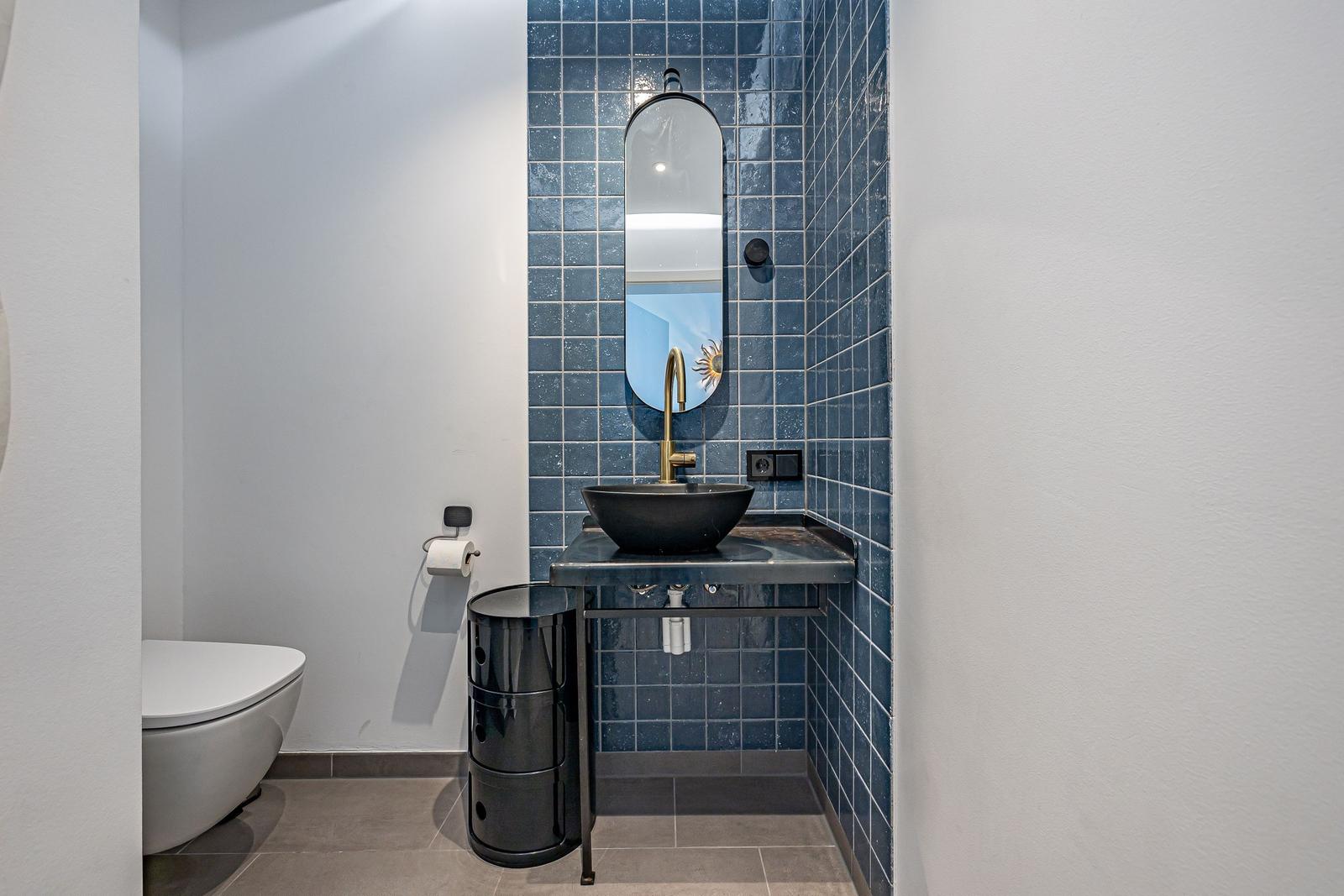 Badezimmer mit blauen Fliesen, Waschbecken und Spiegel