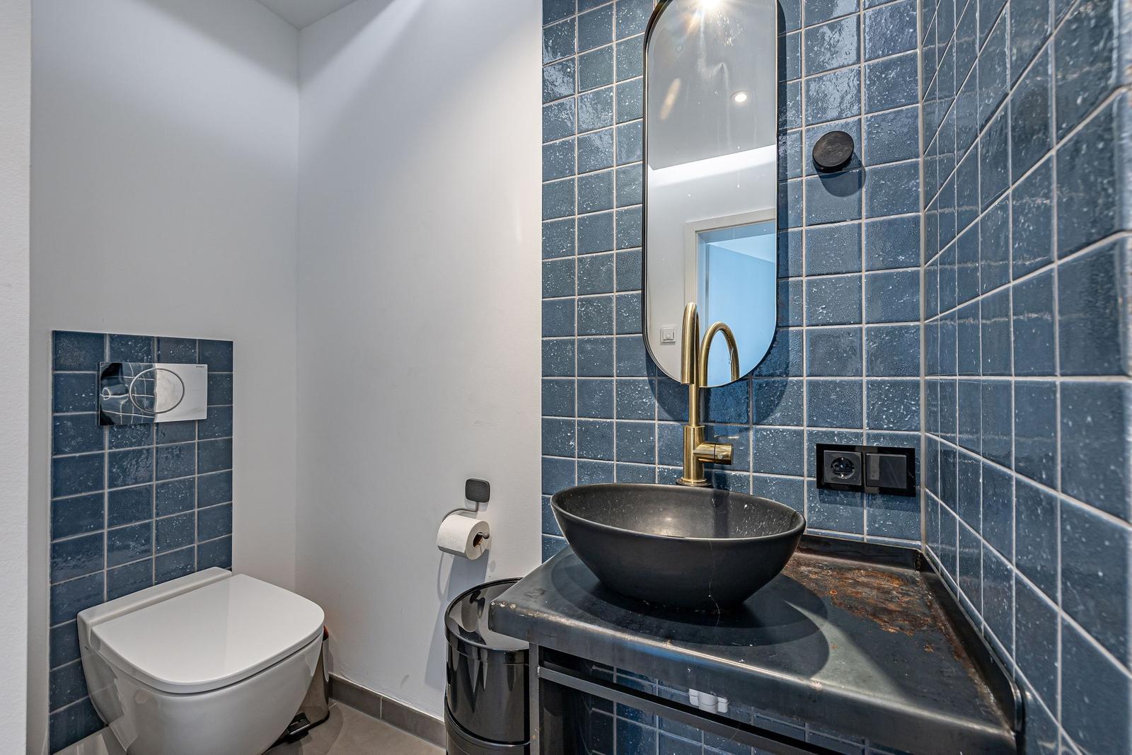 Badezimmer mit blauen Fliesen, Waschbecken und Spiegel