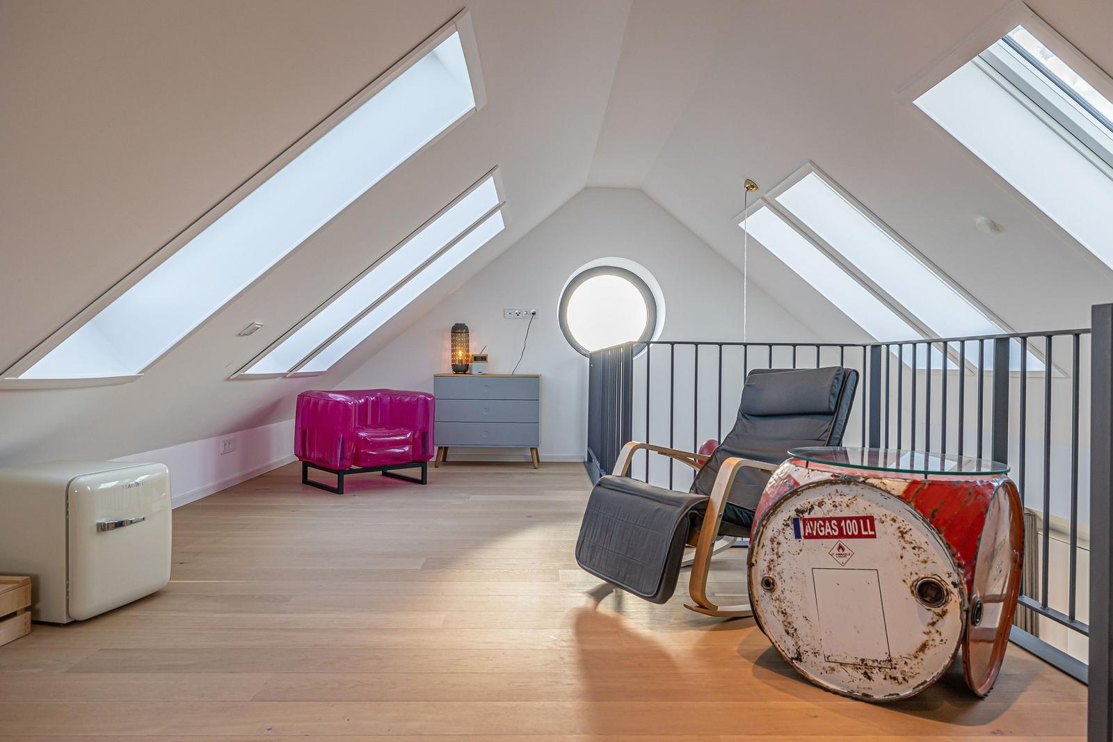Dachgeschosszimmer mit Dachschrägen, Fenstern und Möbeln.